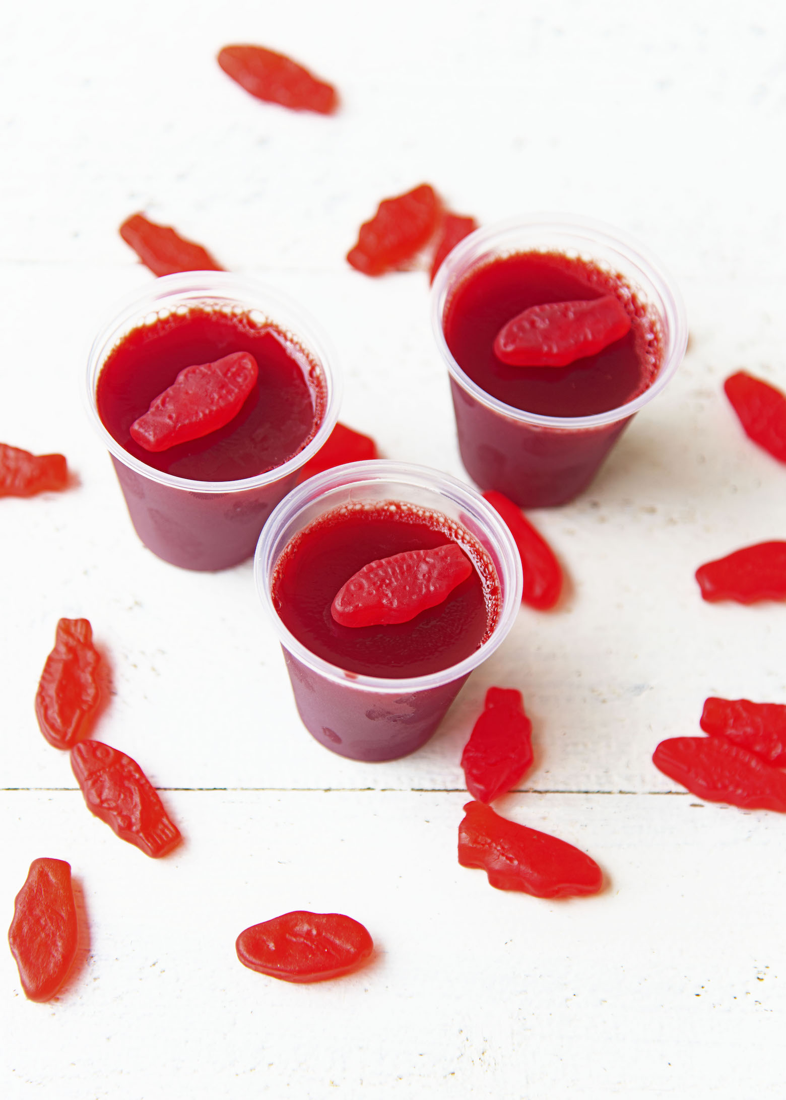 Cluster of three Swedish Fish Jello Shots with Swedish fish scattered around them.