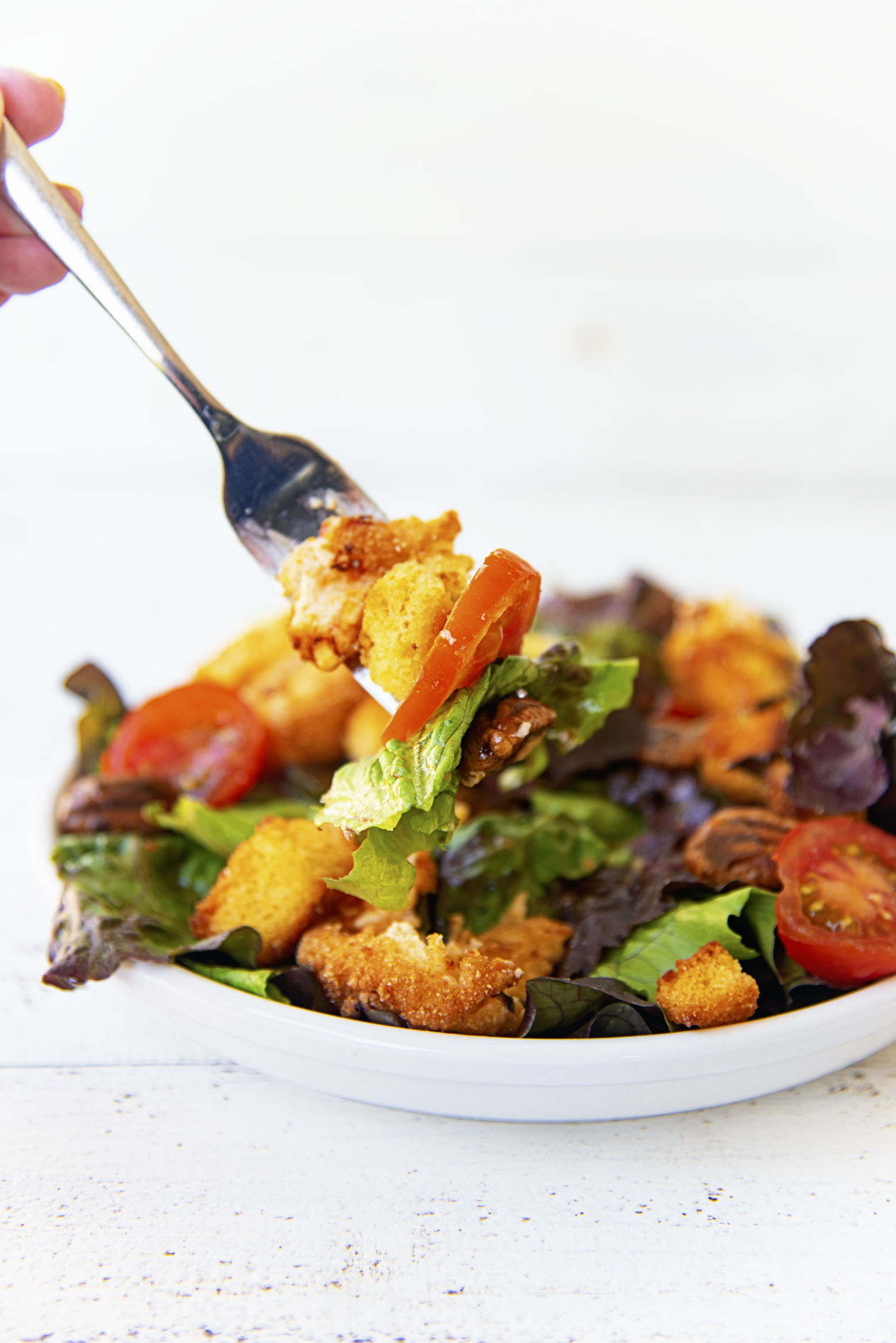 Close up shot of salad on a fork with the remaining salad in the backgroun. 