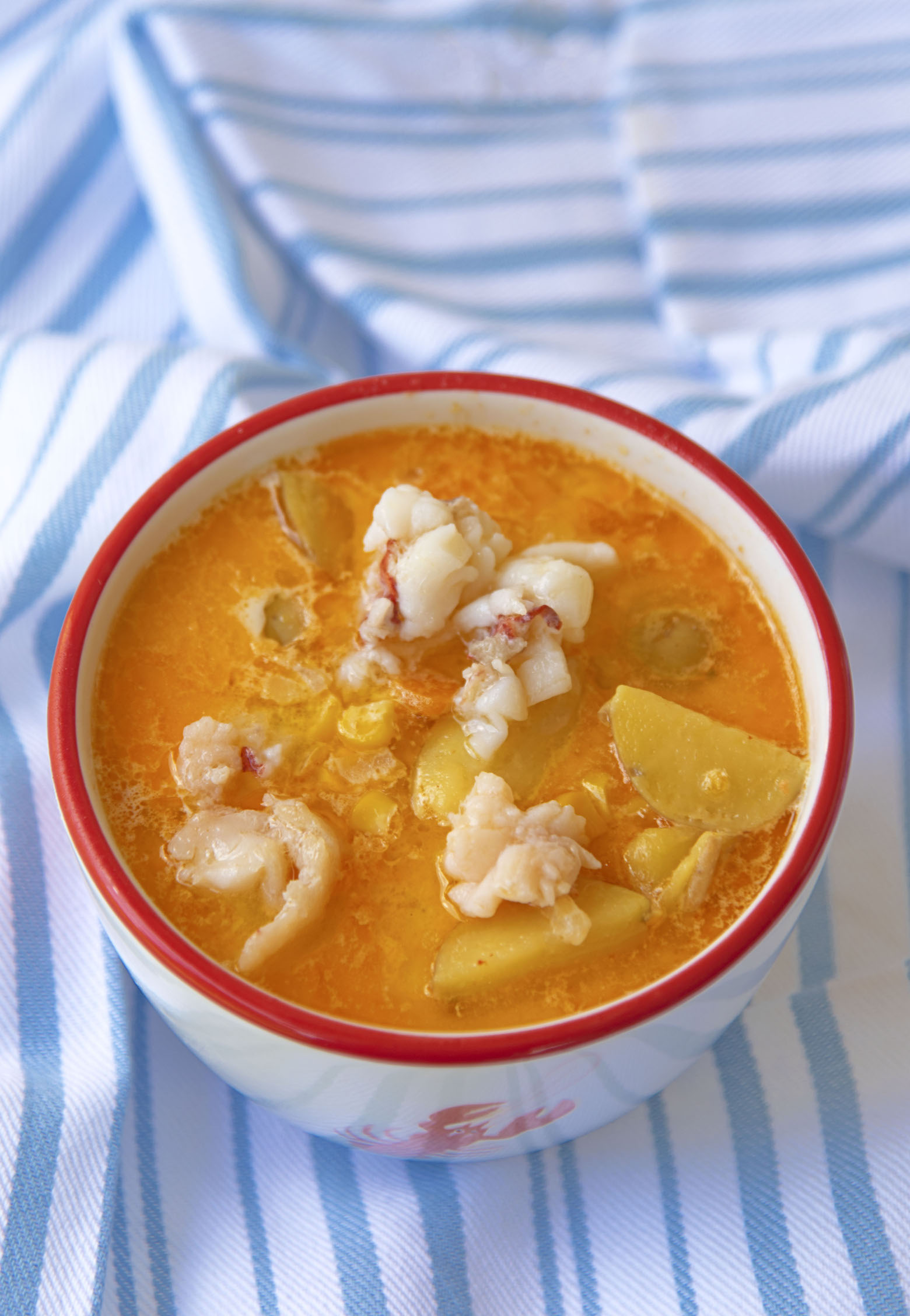 Bowl of Lobster Sweet Corn Chowder with a close up of the lobster and potatoes in the chowder.