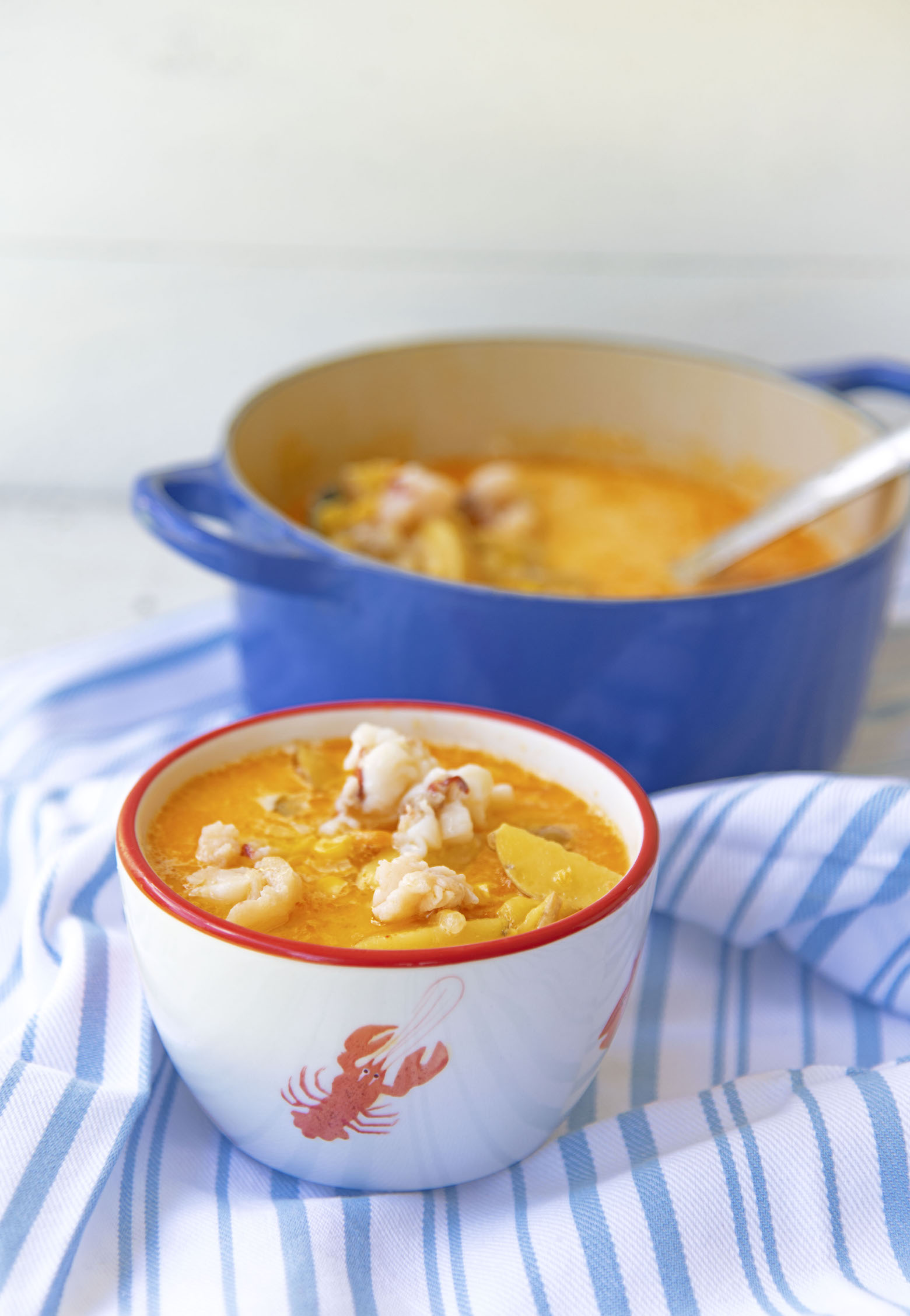 Bowl of chowder with pot of it in the background. 