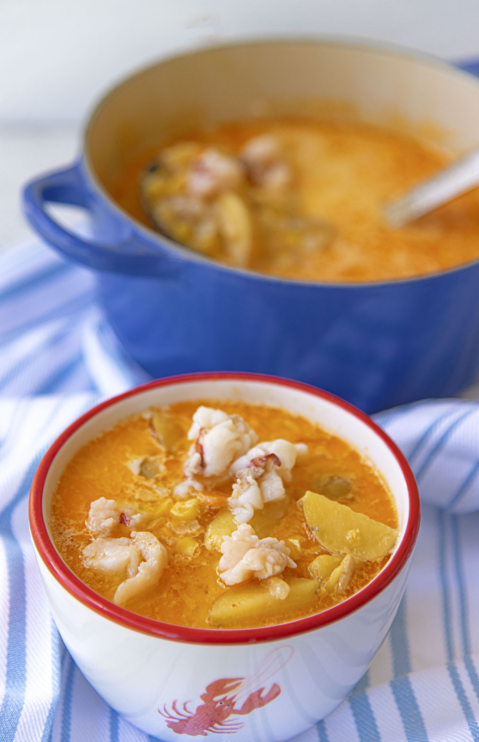 Bowl of Lobster Sweet Corn Chowder with the pot of the chowder in the background. 