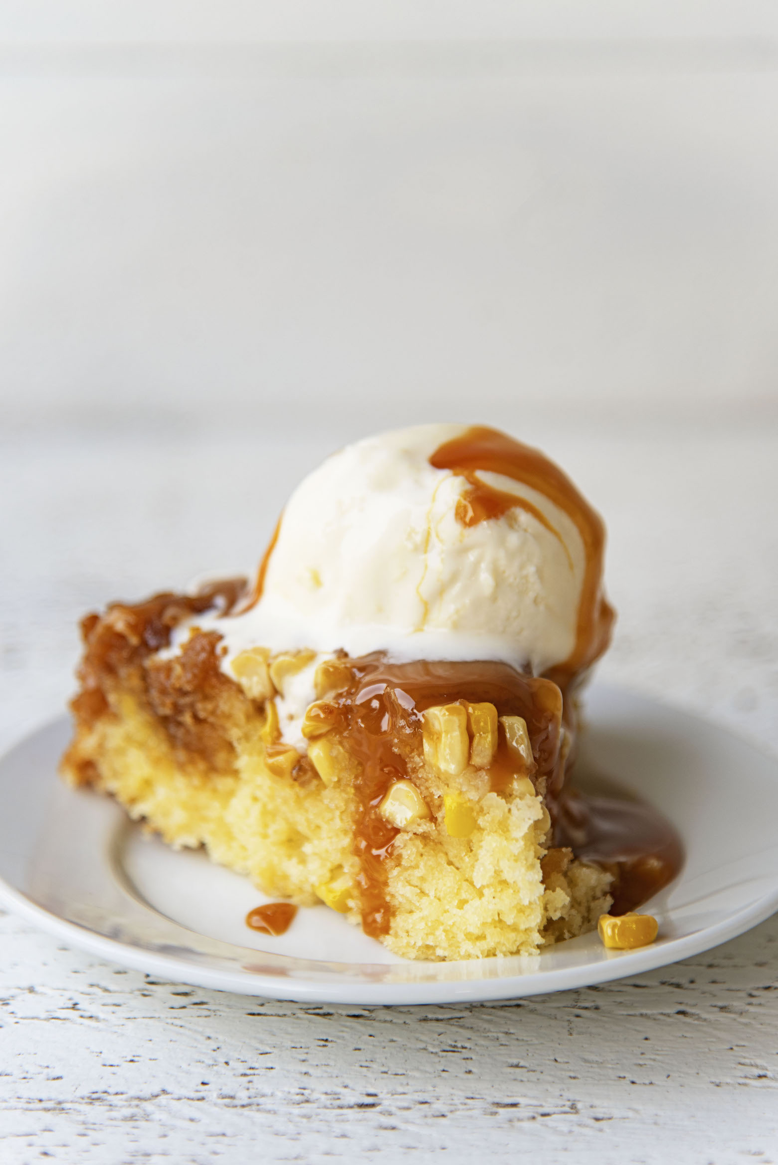 Side view of a cut piece of cake with ice cream and caramel sauce.