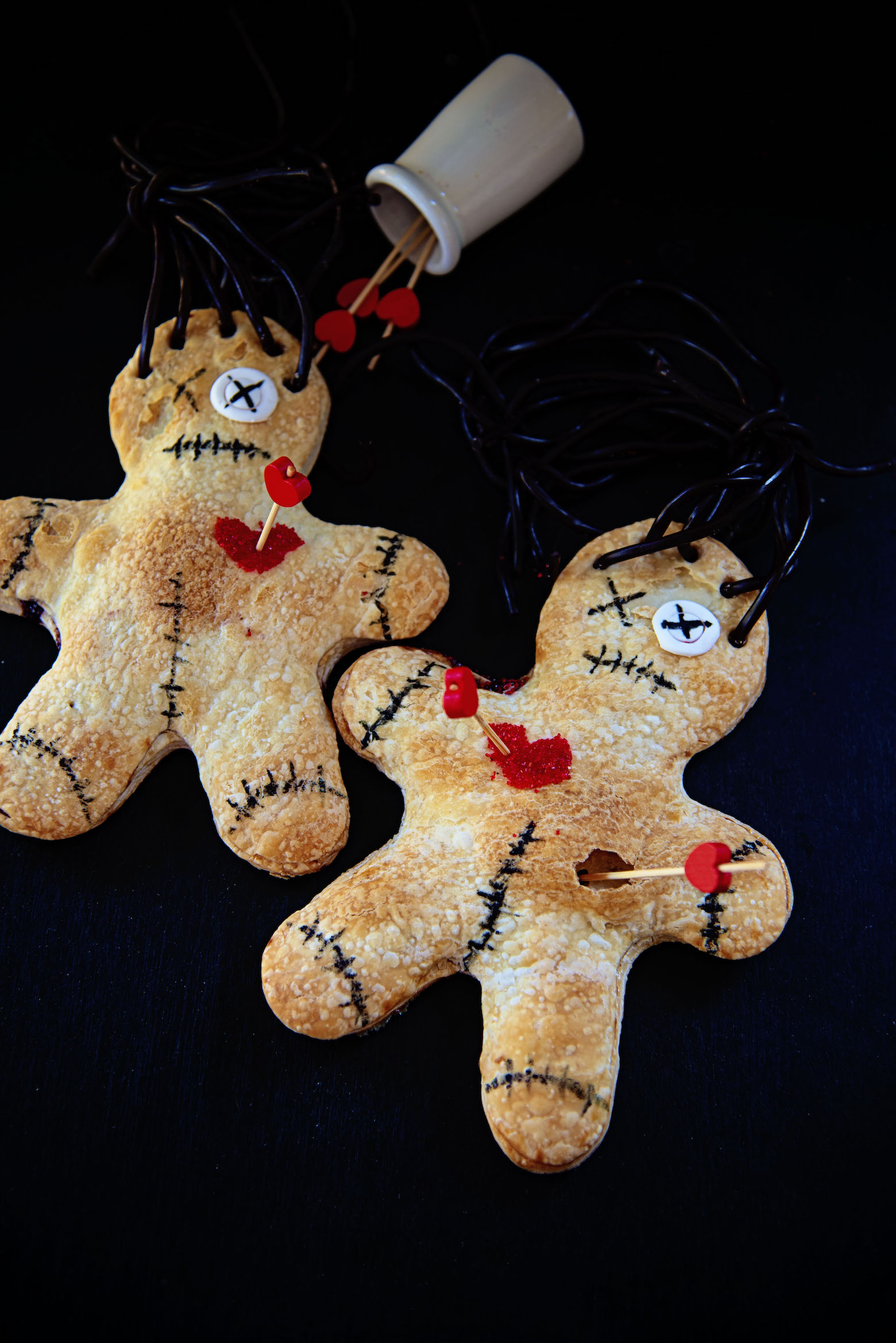 Two Voodoo Doll Hand Pies on a black background