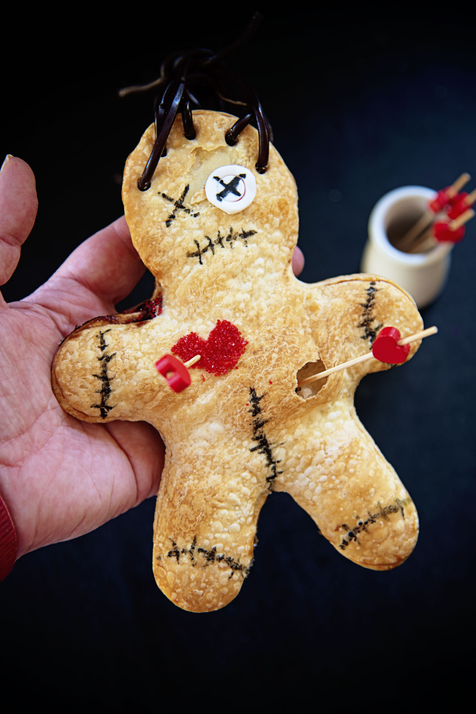 Voodoo Doll Hand Pies being held in a hand for up close shot.
