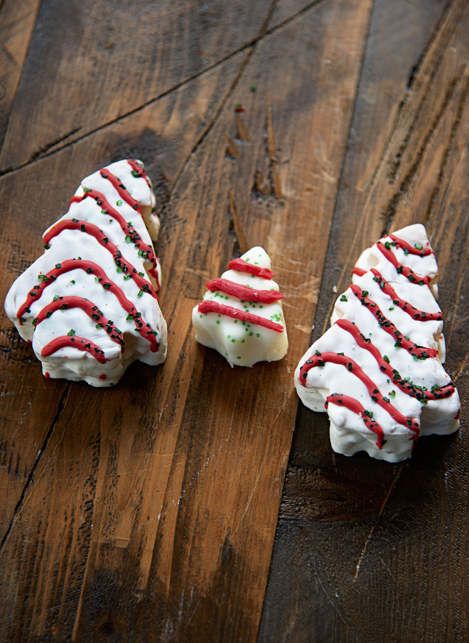 A piece of Christmas Tree Cake Fudge between two Little Debbie Christmas Tree Cakes
