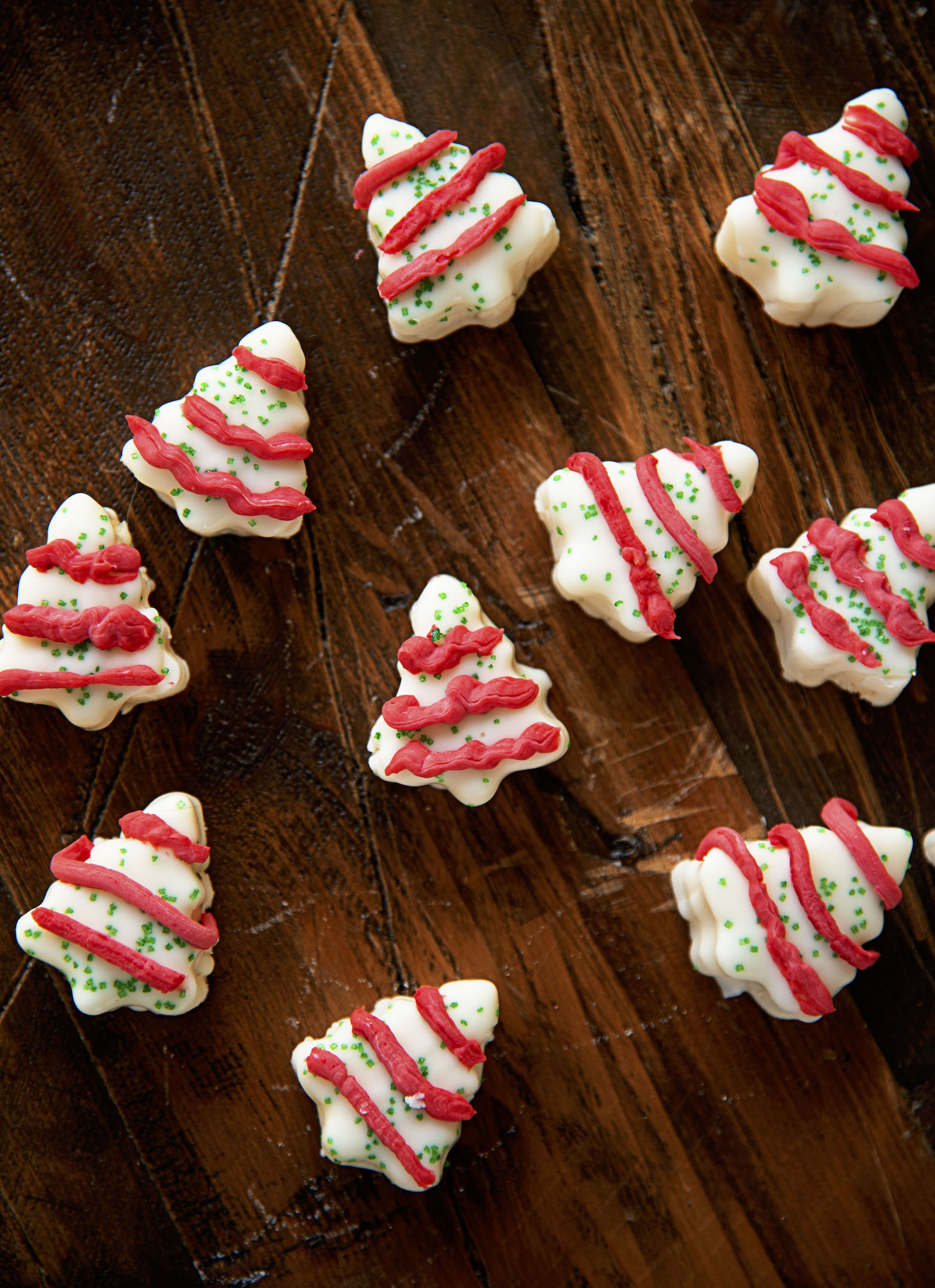 Overhead shot of a bunch of scattered Christmas Tree Cake Fudge on a wood board.