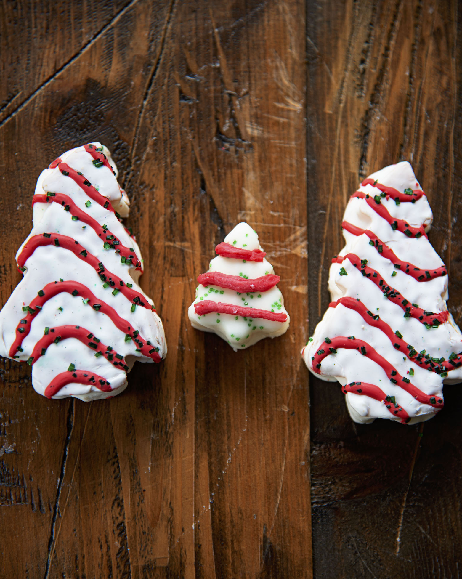 A piece of Christmas Tree Cake Fudge between two Little Debbie Christmas Tree Cakes