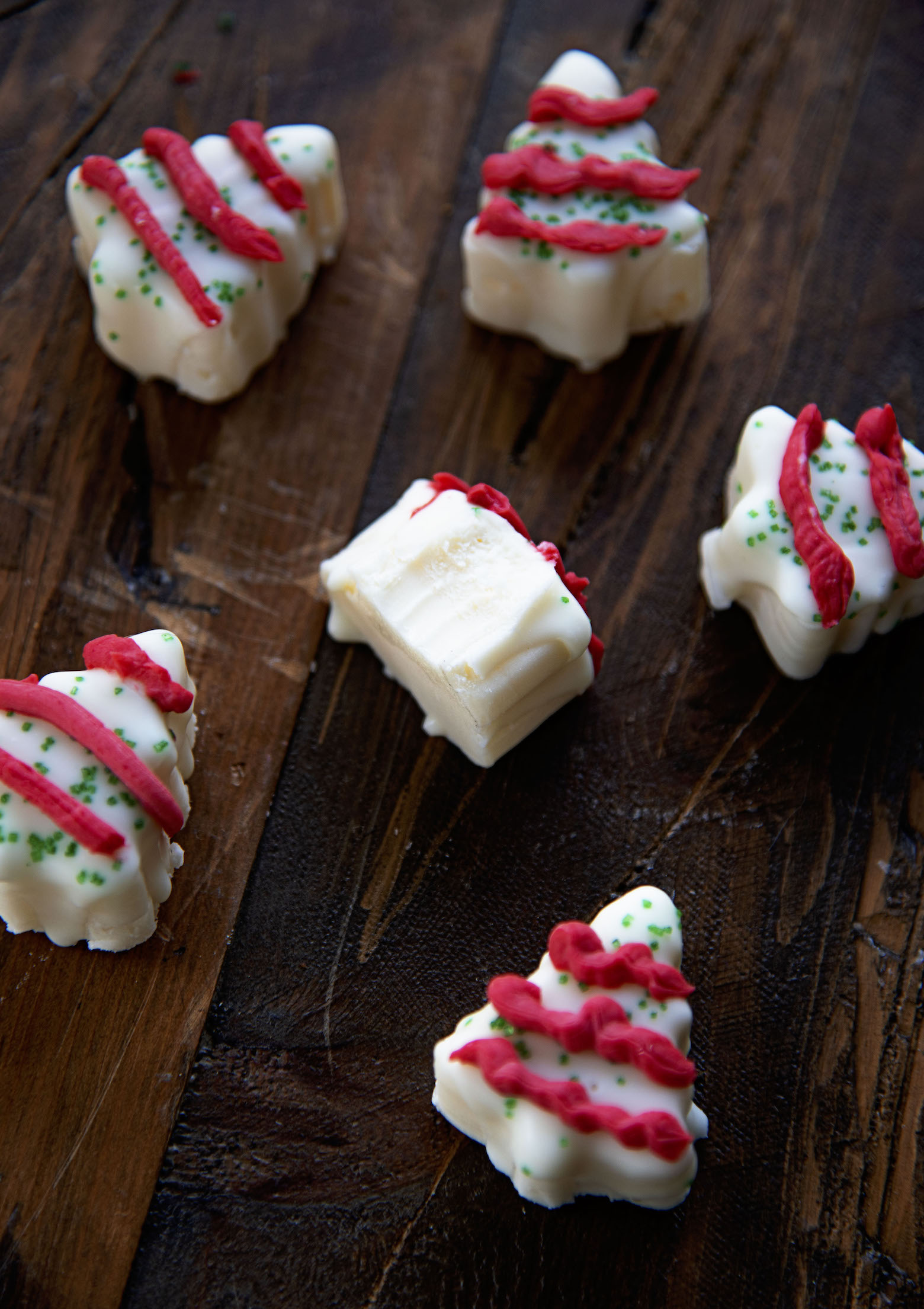 Christmas Tree Cake Fudge pieces scattered with a piece of fudge with a chunk bit out of it. 