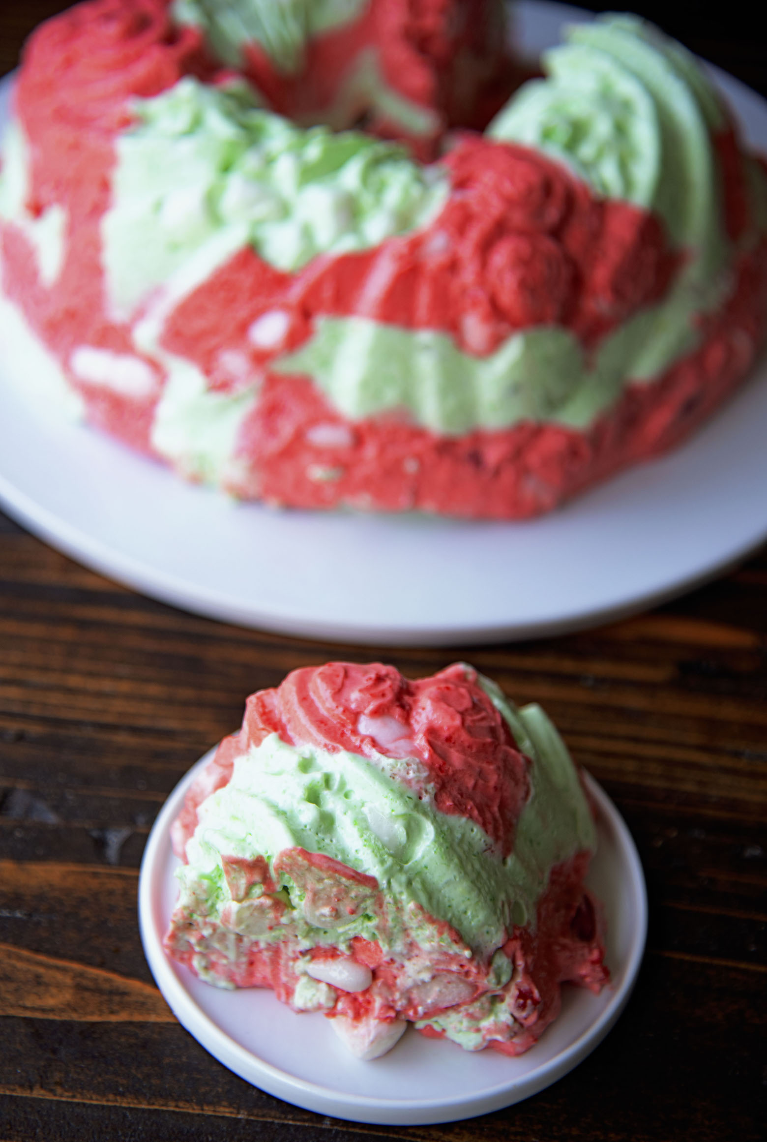 A slice of jello mold on a small appetizer plate with remaining jello mold in the background.