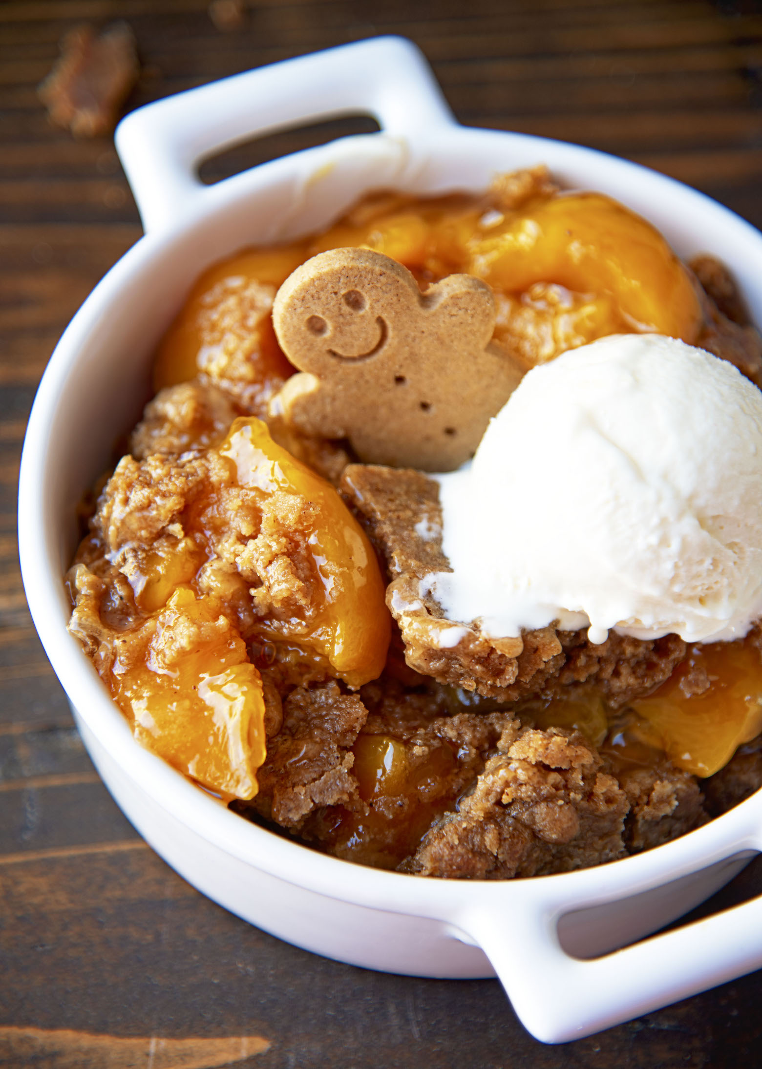 Close up of the Gingerbread Peach Dump Cake with a mini gingerbread man cookie sticking out from the cake. 