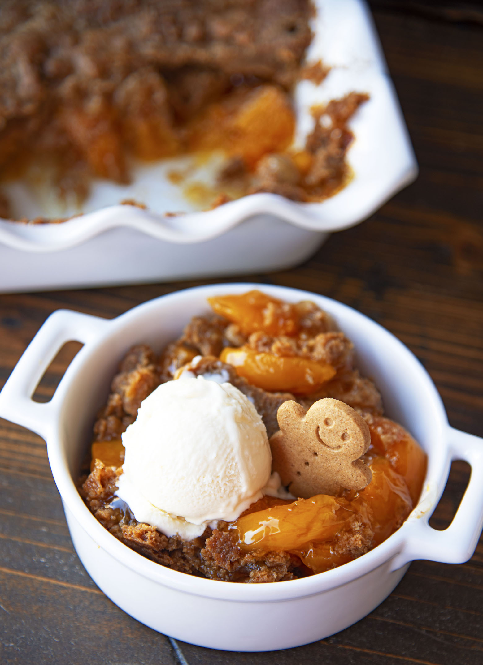 Three quarter shot of the dump cake in a round container with the remaining dump cake in the back.
