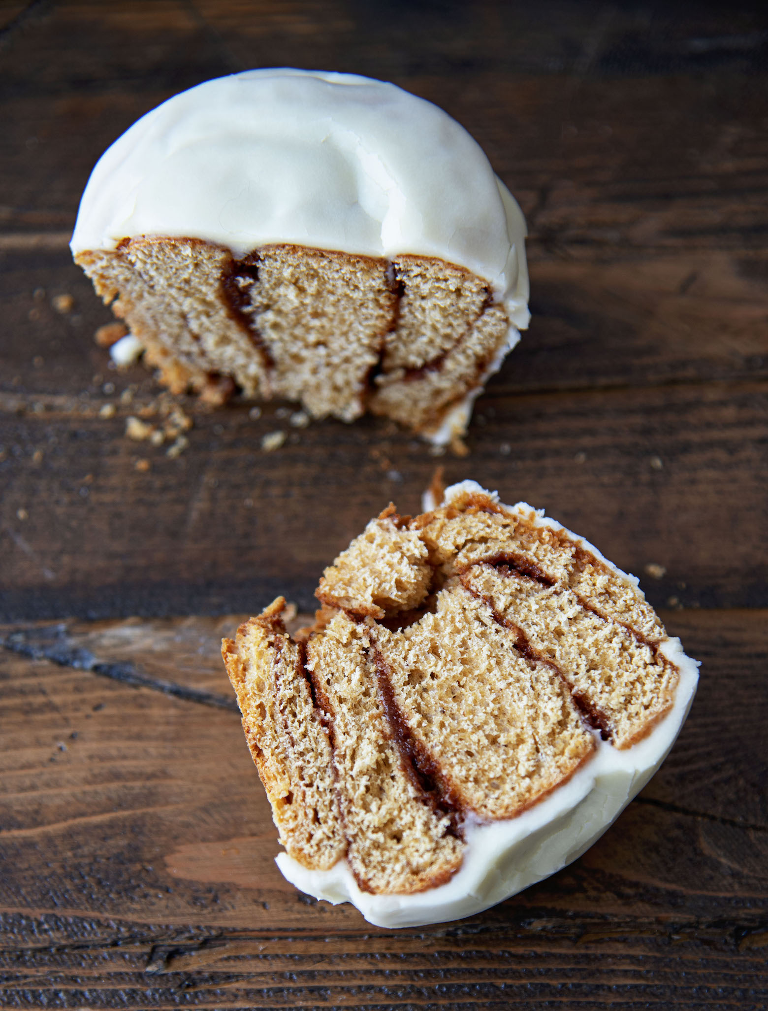 Orange Gingerbread Cinnamon Roll cut in half with focus on one half of the roll.