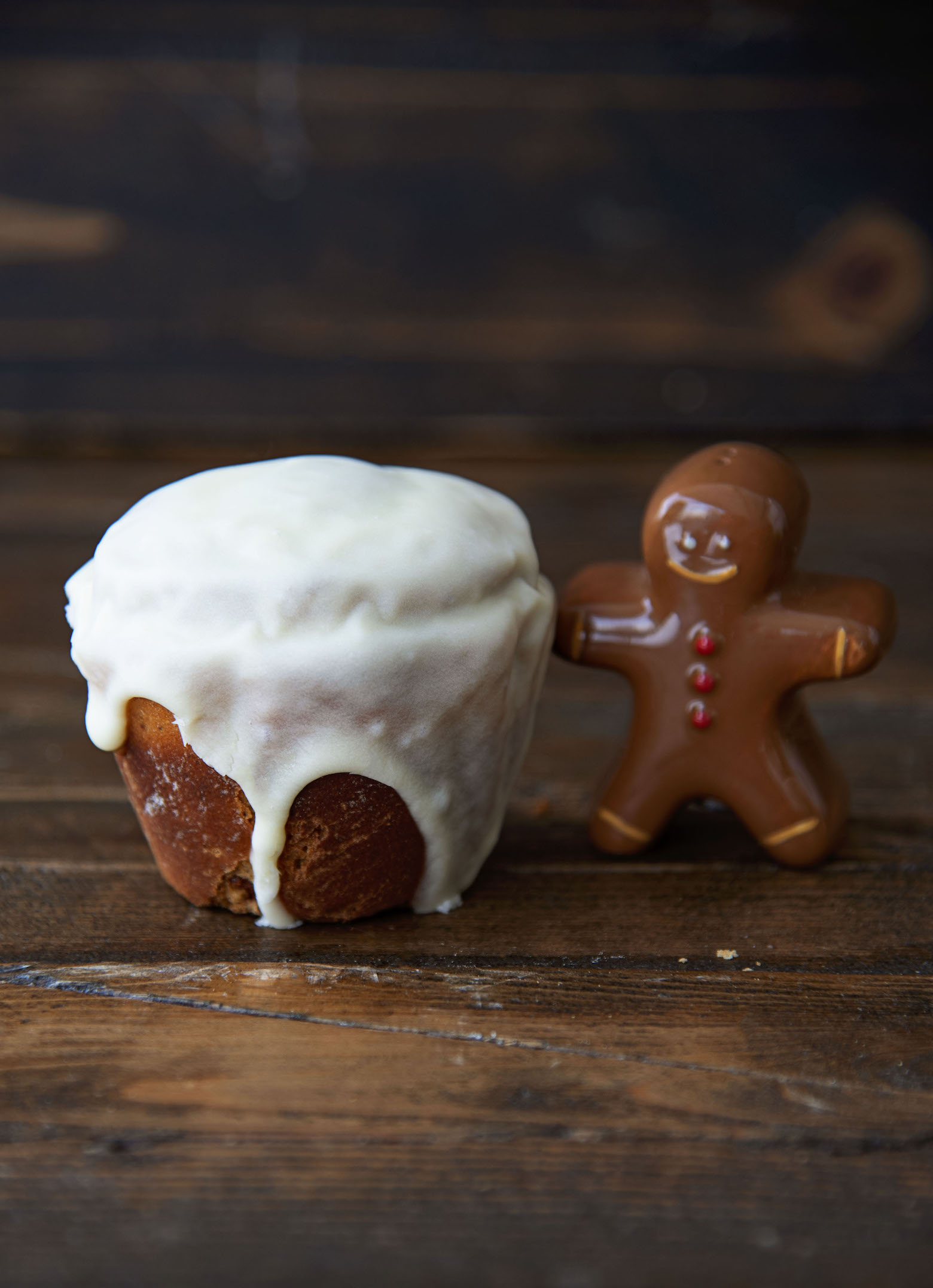 Single cinnamon roll next to a mini gingerbread man. 