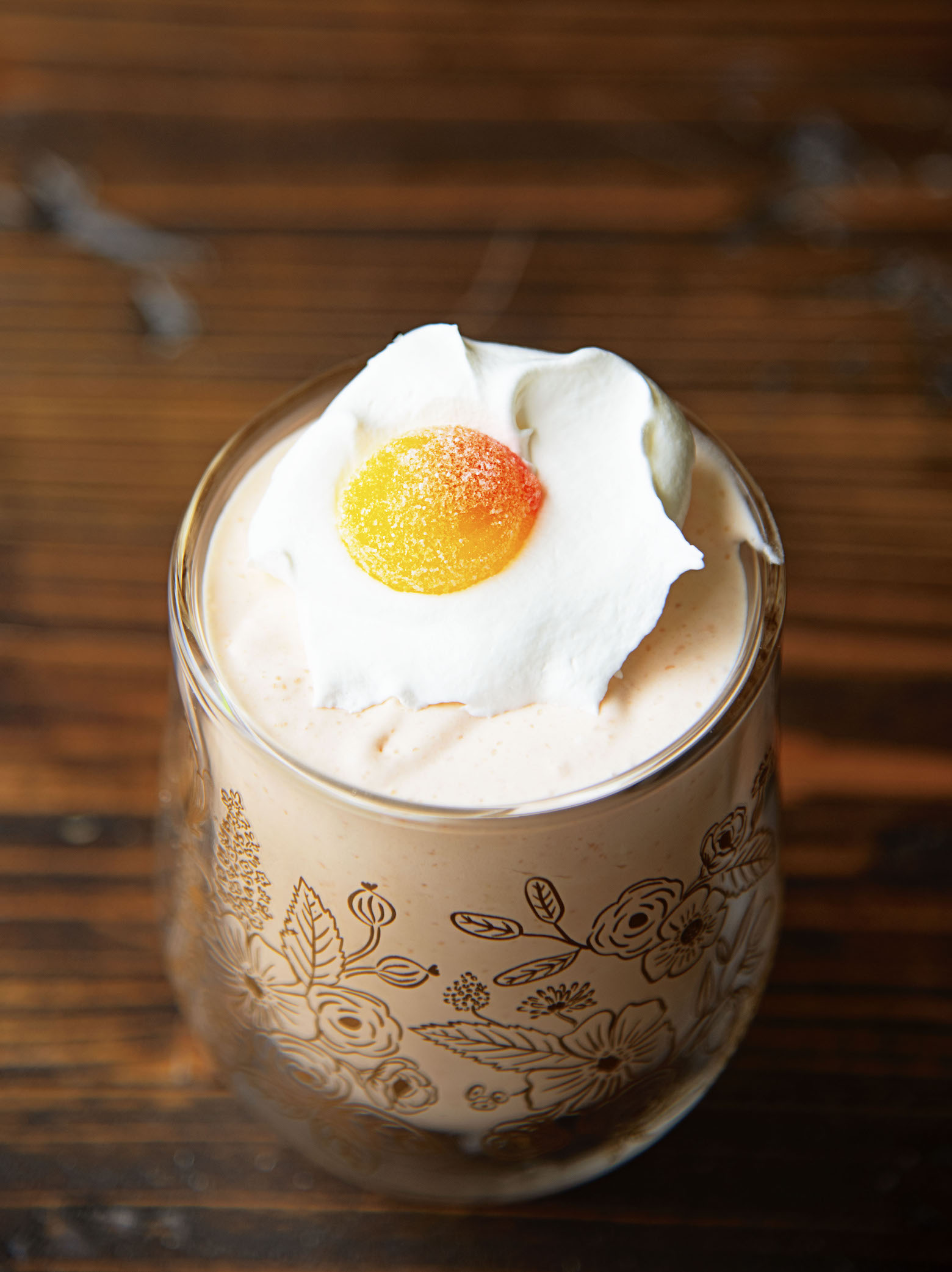 Three quarter shot of a single Peach Bellini Jello Salad in a glass with focus on the peach candy on top of whipped cream