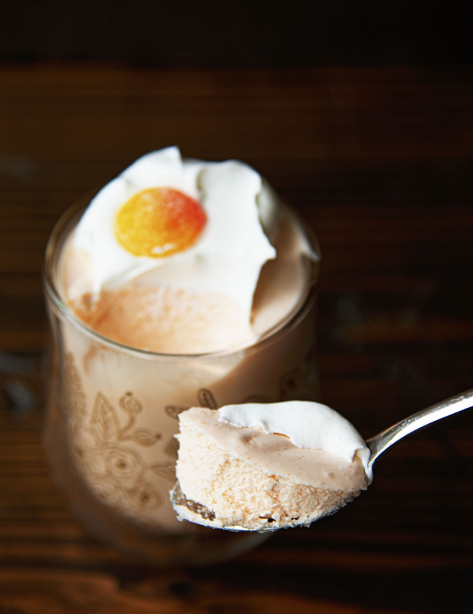 Close up of the Peach Bellini Jello Salad on a spoon with remaining amount in the glass behind the spoon