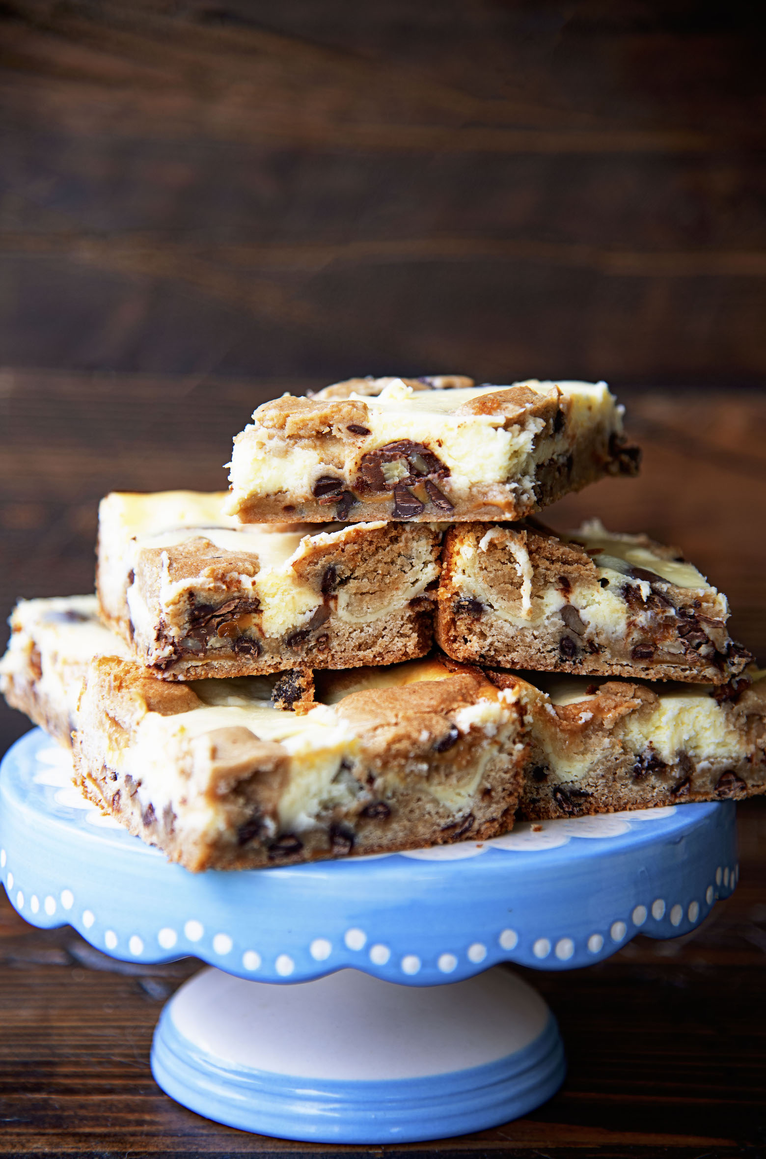 Side view of Caramel Turtle Cheesecake Bars on a blue cake plate. 