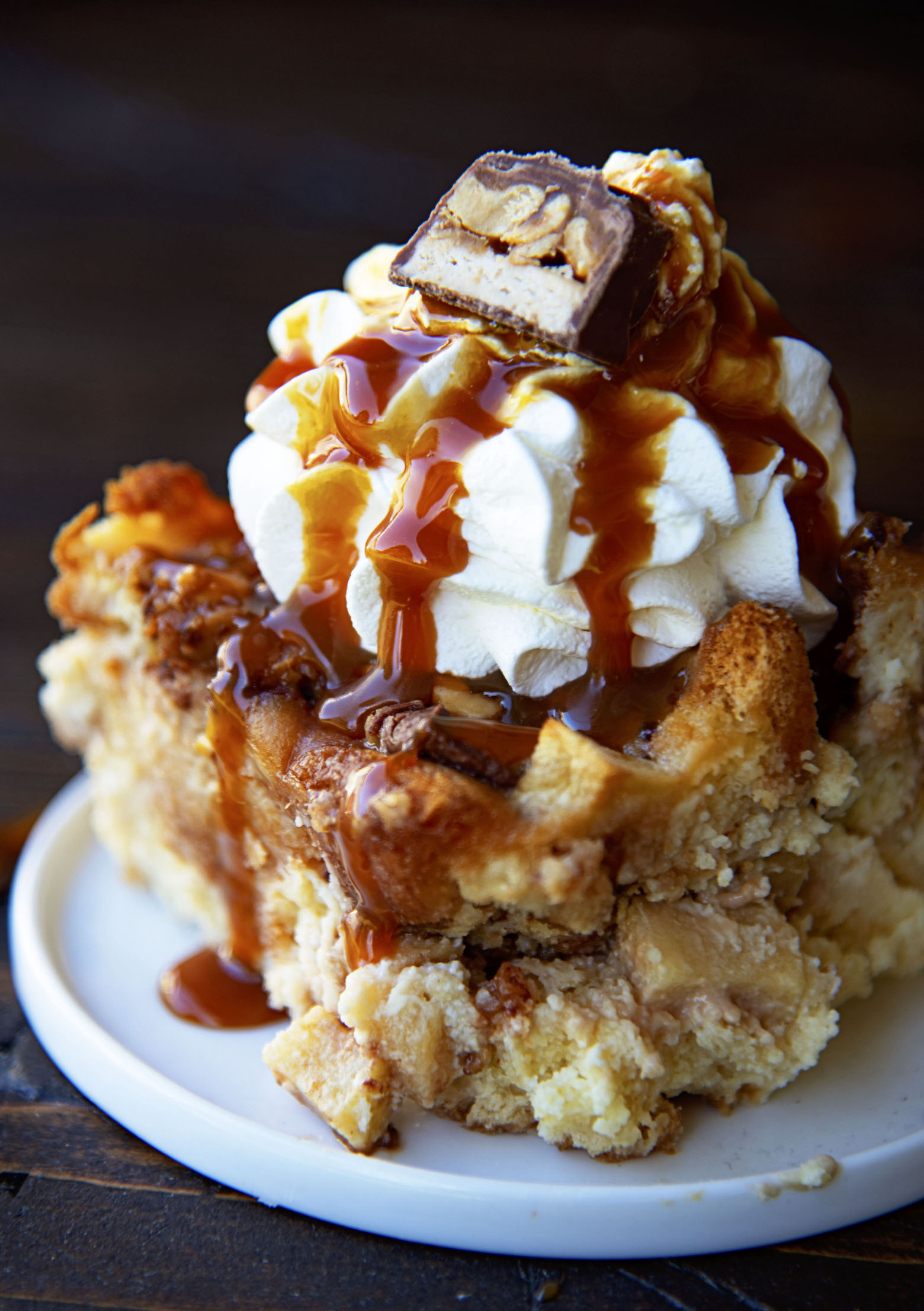 Close up of a slice of bread pudding with whipped cream and caramel sauce.