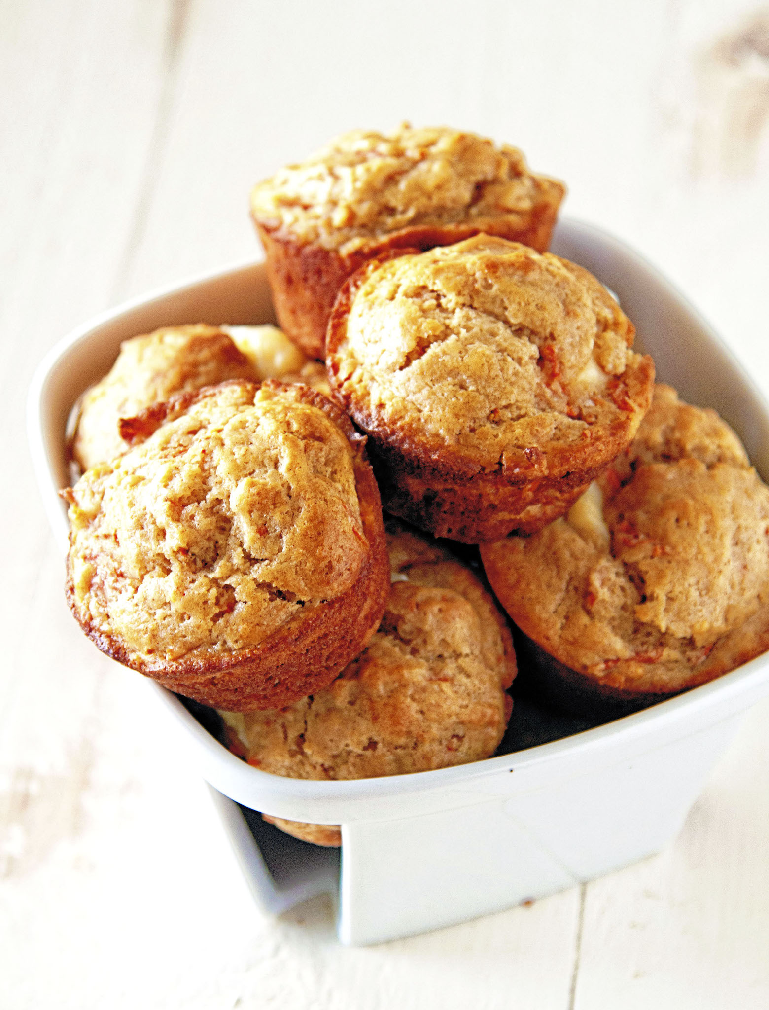 Overflowing small white basket full of the muffins. 