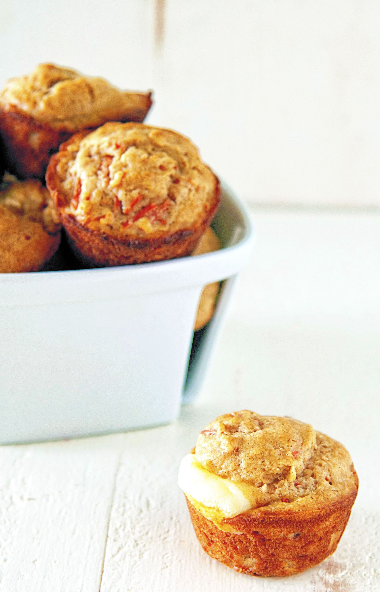 One muffin in front of a small basket of muffins.