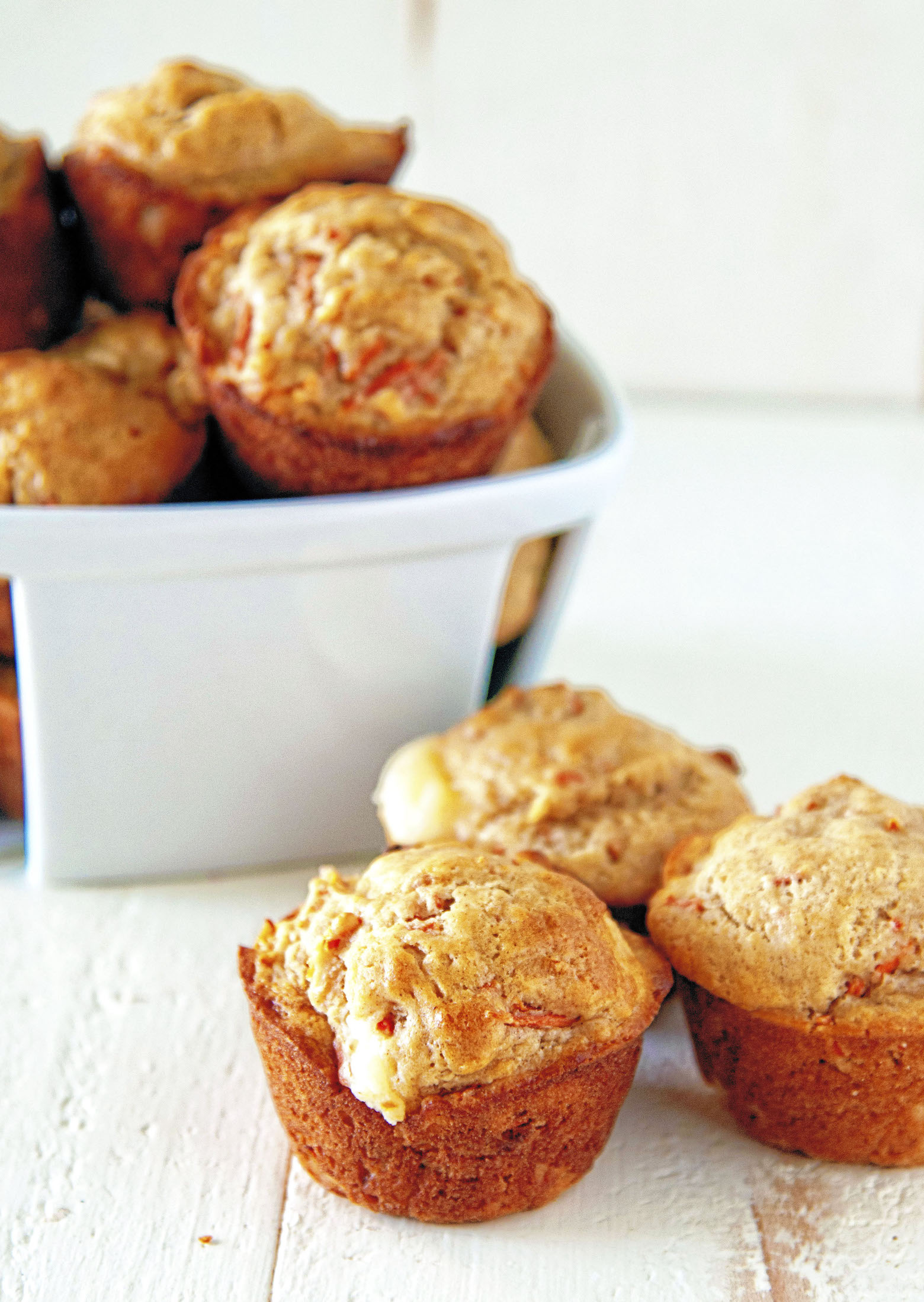 Three muffins in front of a small basket of muffins.