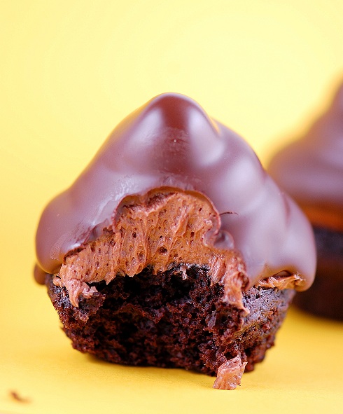 Mini Hit Hat cupcake with a bite out of it exposing the frosting underneath the chocolate coating layer.