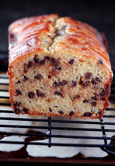 Side view of the cake with all the chocolate chips exposed and on a wire rack with glaze below. 