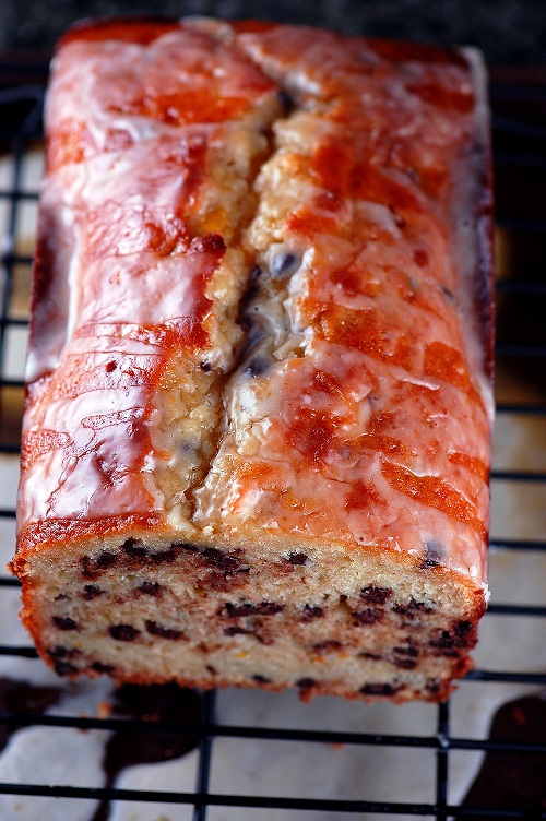 Overhead shot of the yogurt cake with a slice off to show the inside as it rest on a wire rack with glaze under it.