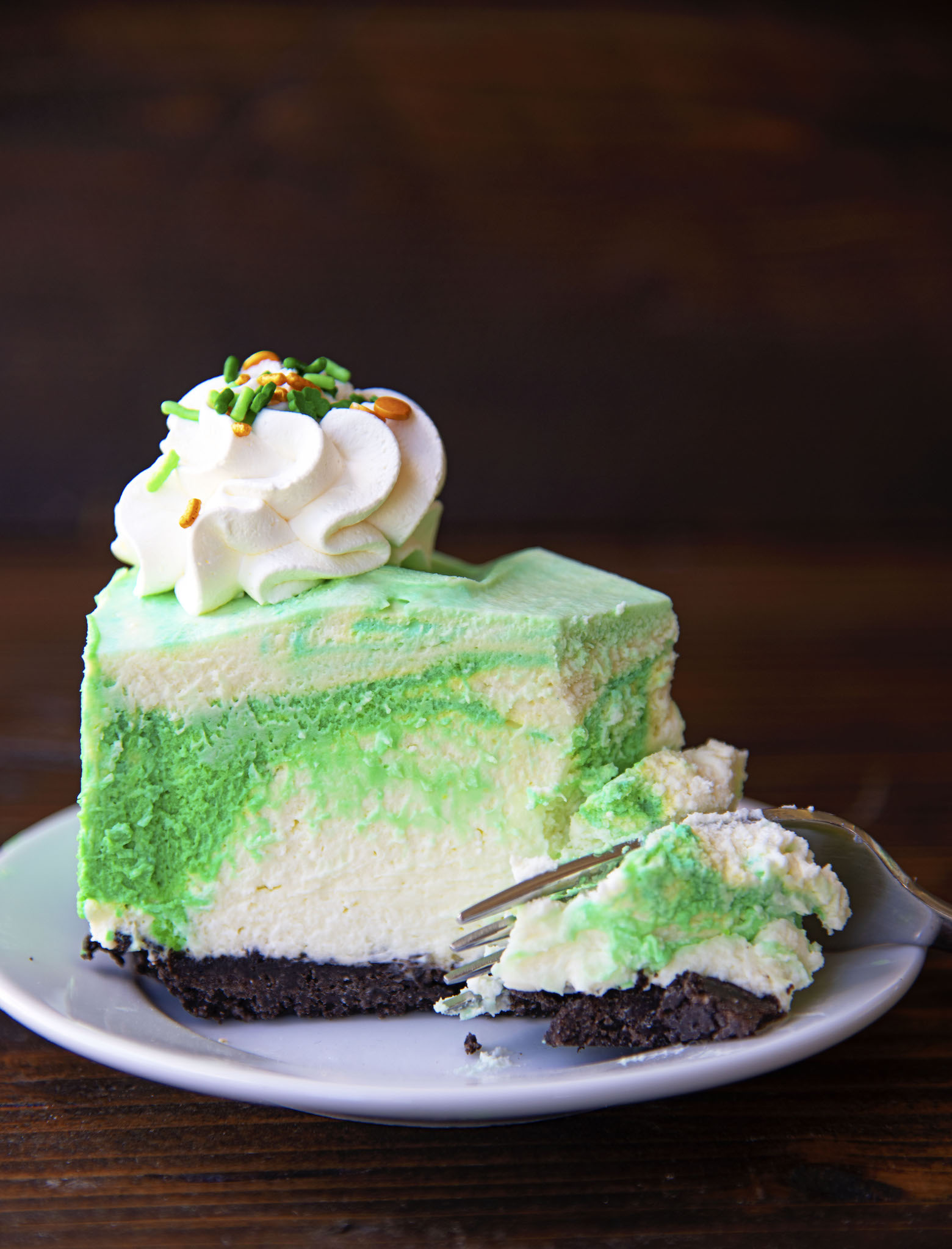 Single slice of mousse cake on a small white plate with a fork cutting through it. 