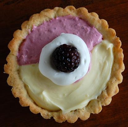 Overhead view of the  Blackberry and Lime Tart with whipped cream and a fresh blackberry in the center