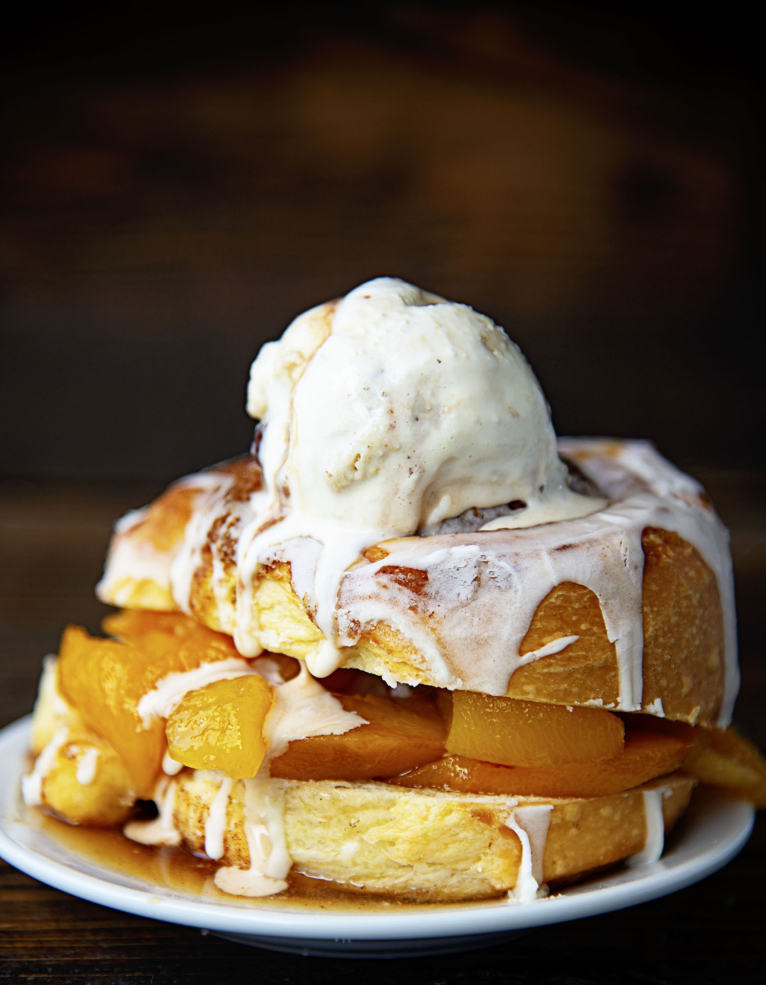 Side view of Cinnamon Roll Peach Shortcake with ice cream on top dripping down. 