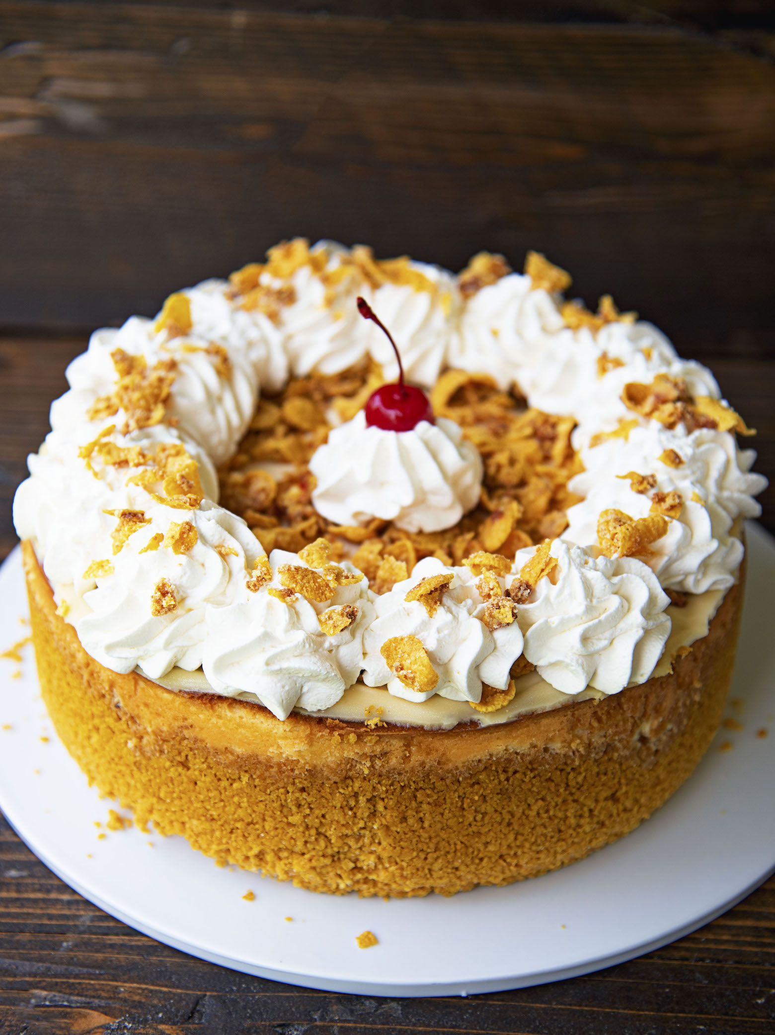 The full Fried Ice Cream Cheesecake on a white platter with brown background. 