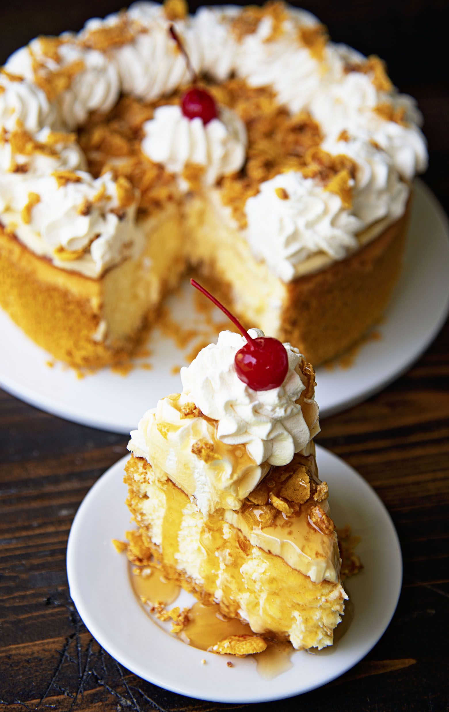 Slice of Fried Ice Cream Cheesecake on a small white plate with remaining cheesecake behind. 