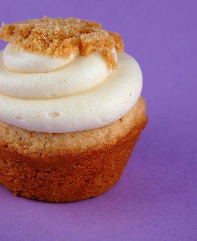 Side view of a single Honey Peanut Butter Crunch Cupcake with purple background