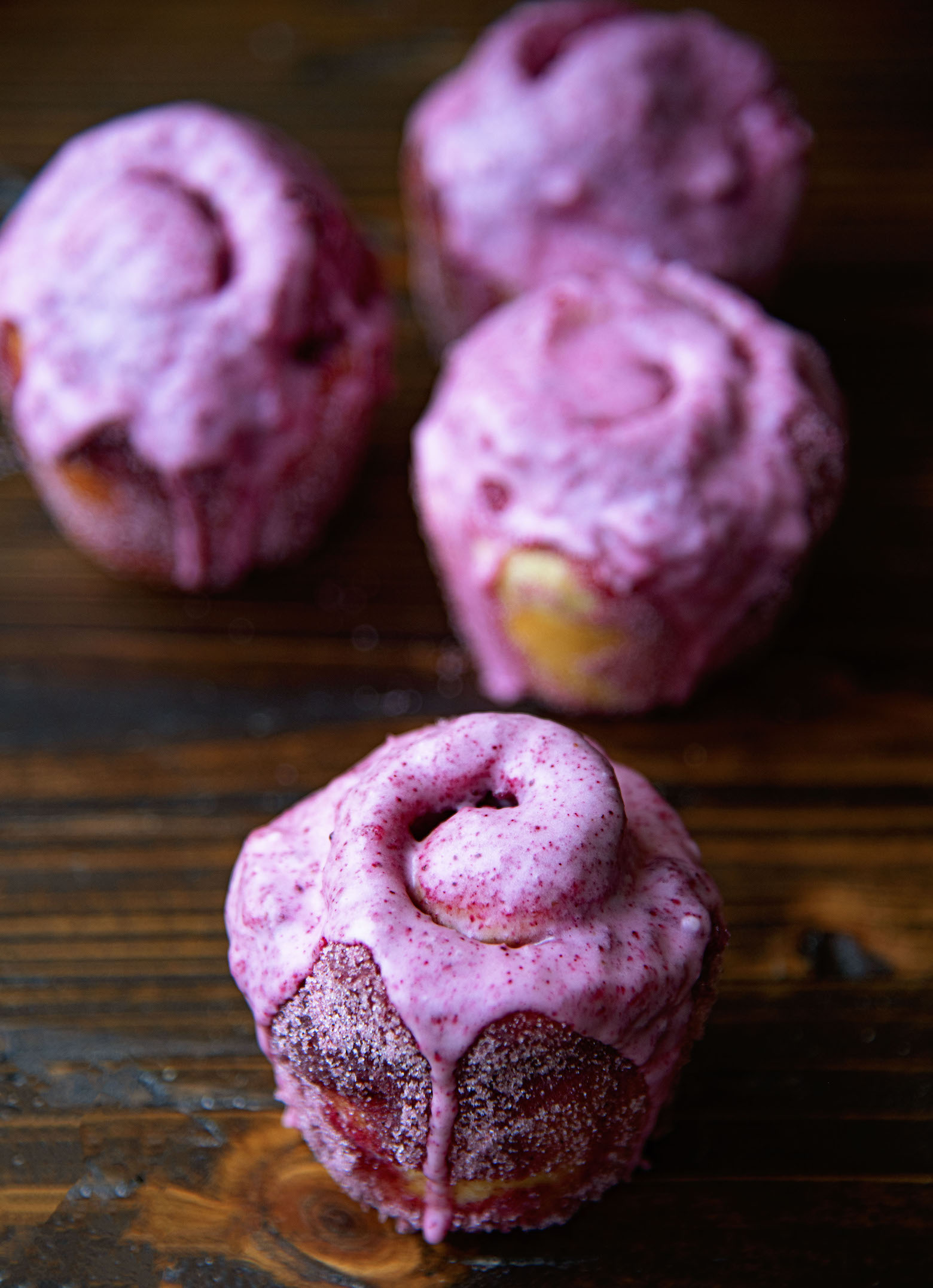 Four Kir Royale Sugar Buns with one in front. All have a purple glaze dripping down them.