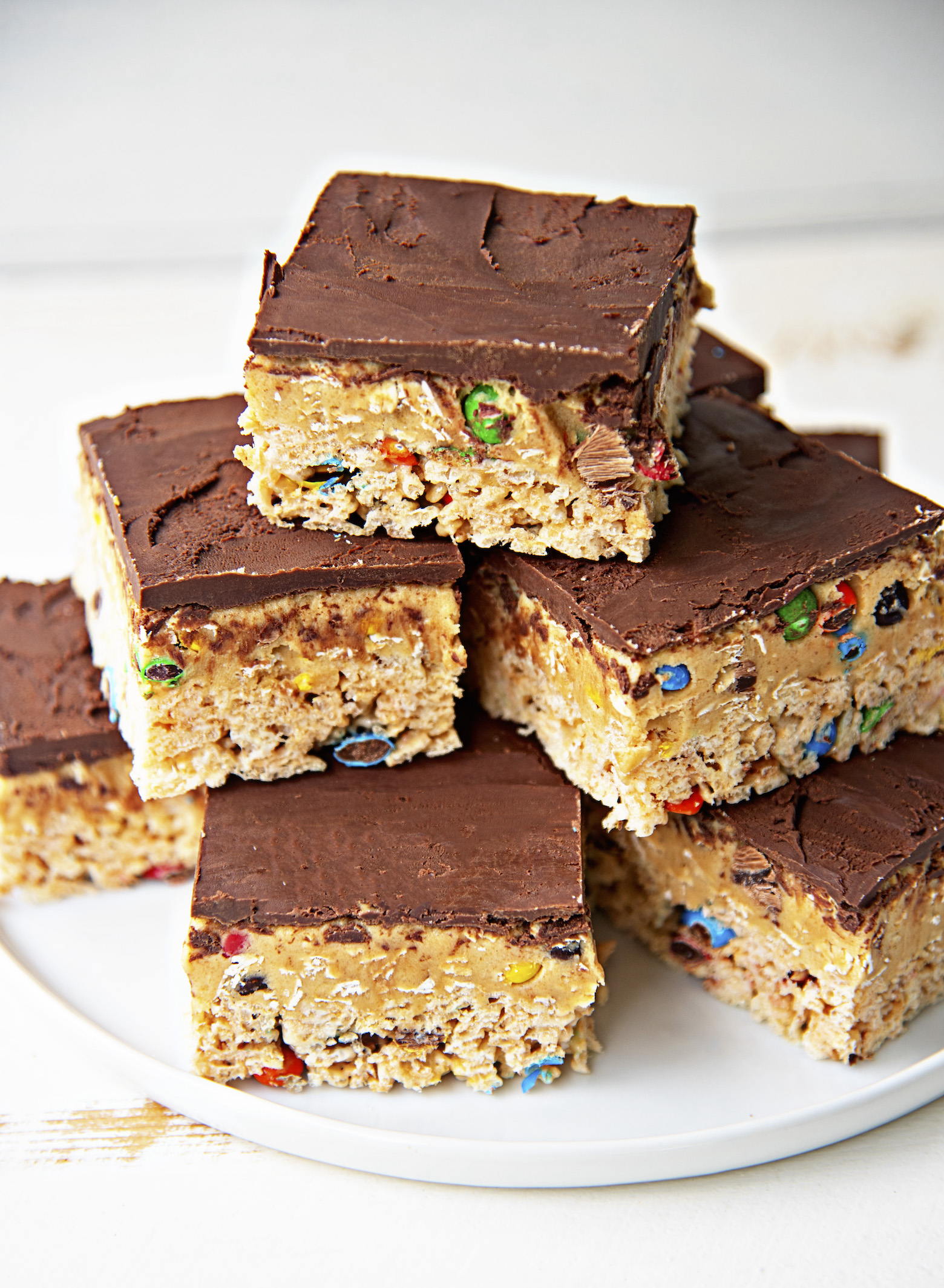 Plate of the Monster Cookie Dough Rice Krispie Treats stacked with the emphasis on the chocolate top.