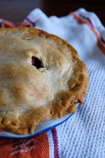 Baked pie in blue pie plate on a tea towel.