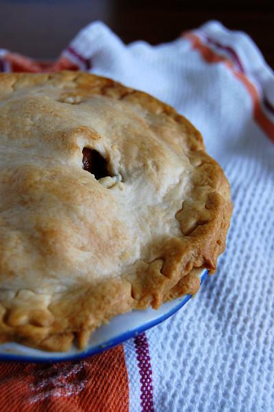 Baked pie in blue pie plate on a tea towel. 