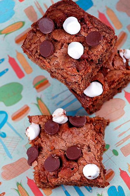 Overhead of three S’mores Graham Cracker Blondie on a background with hamburgers, hot dogs, and other barbeque themes.