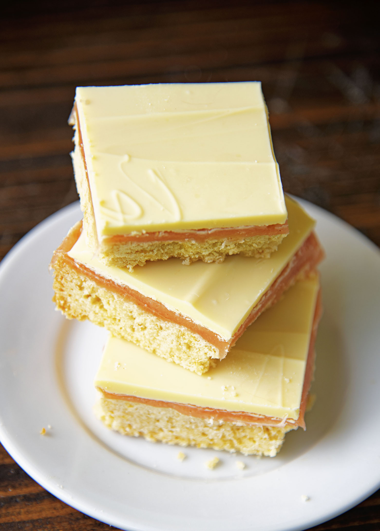 Three quarter view of three Strawberry Lemonade Caramel Bars stacked on top of each other on a small white plate.