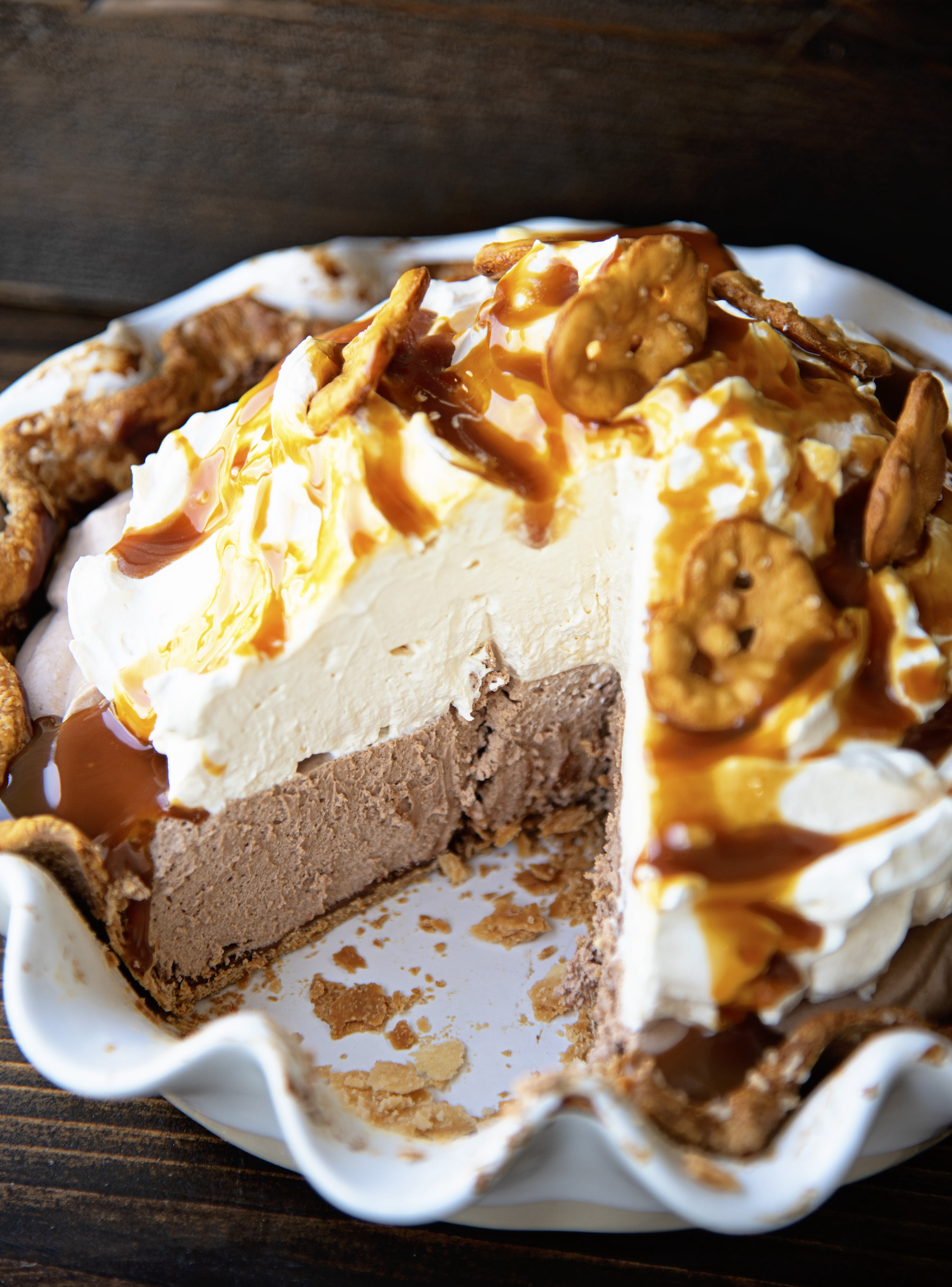 Chocolate Caramel Pretzel Pie in the pie pan with a slice cut out. Focus on the chocolate caramel filling inside. 