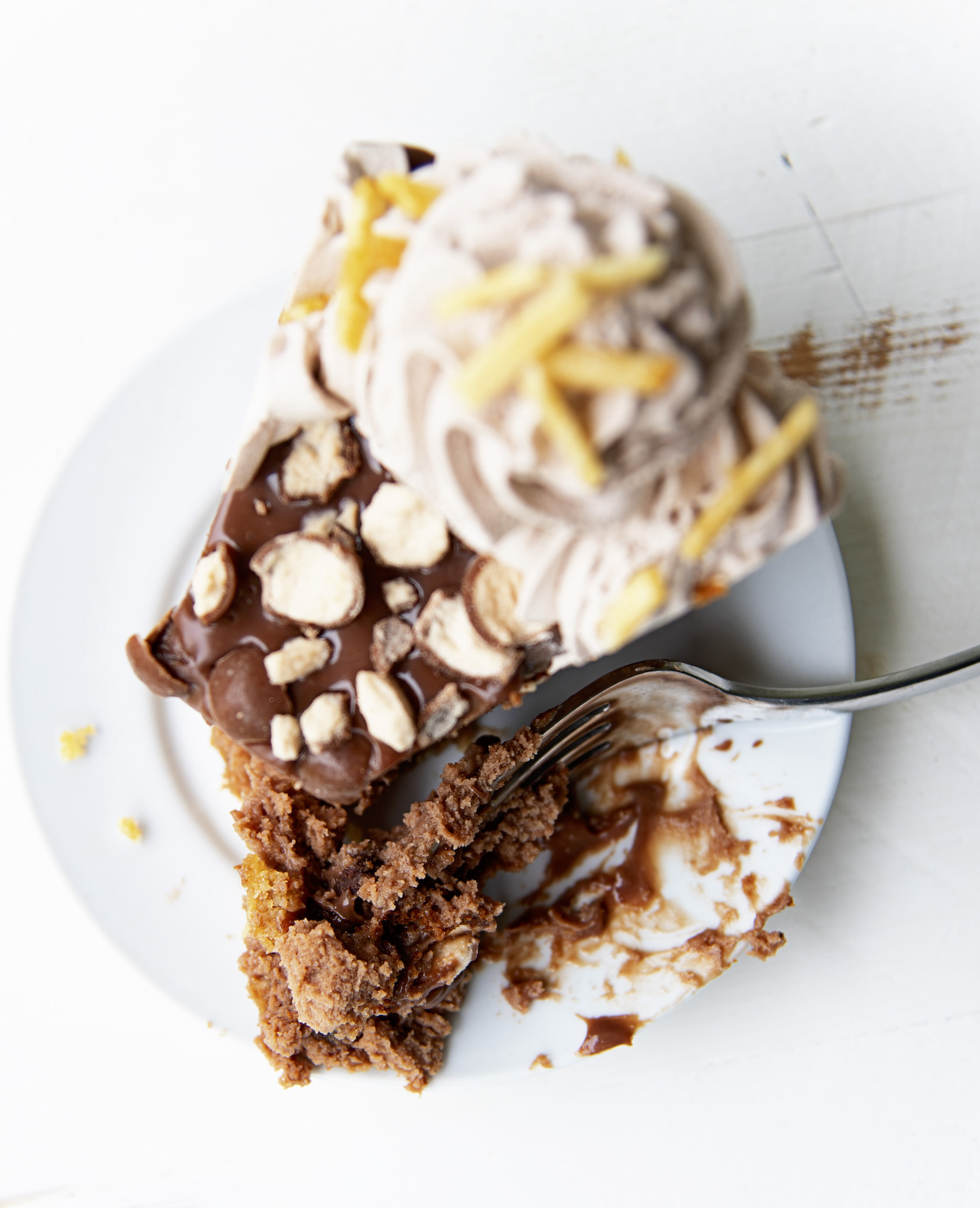 Overhead shot of a single slice of cheesecake with a fork having cut into the cheesecake, with cheesecake still on the fork.