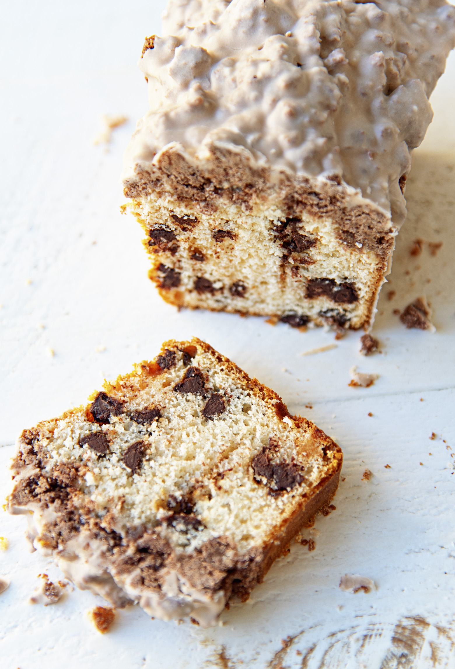 Single crumb cake with a slice out in front of it exposing the chocolate chip filling. 