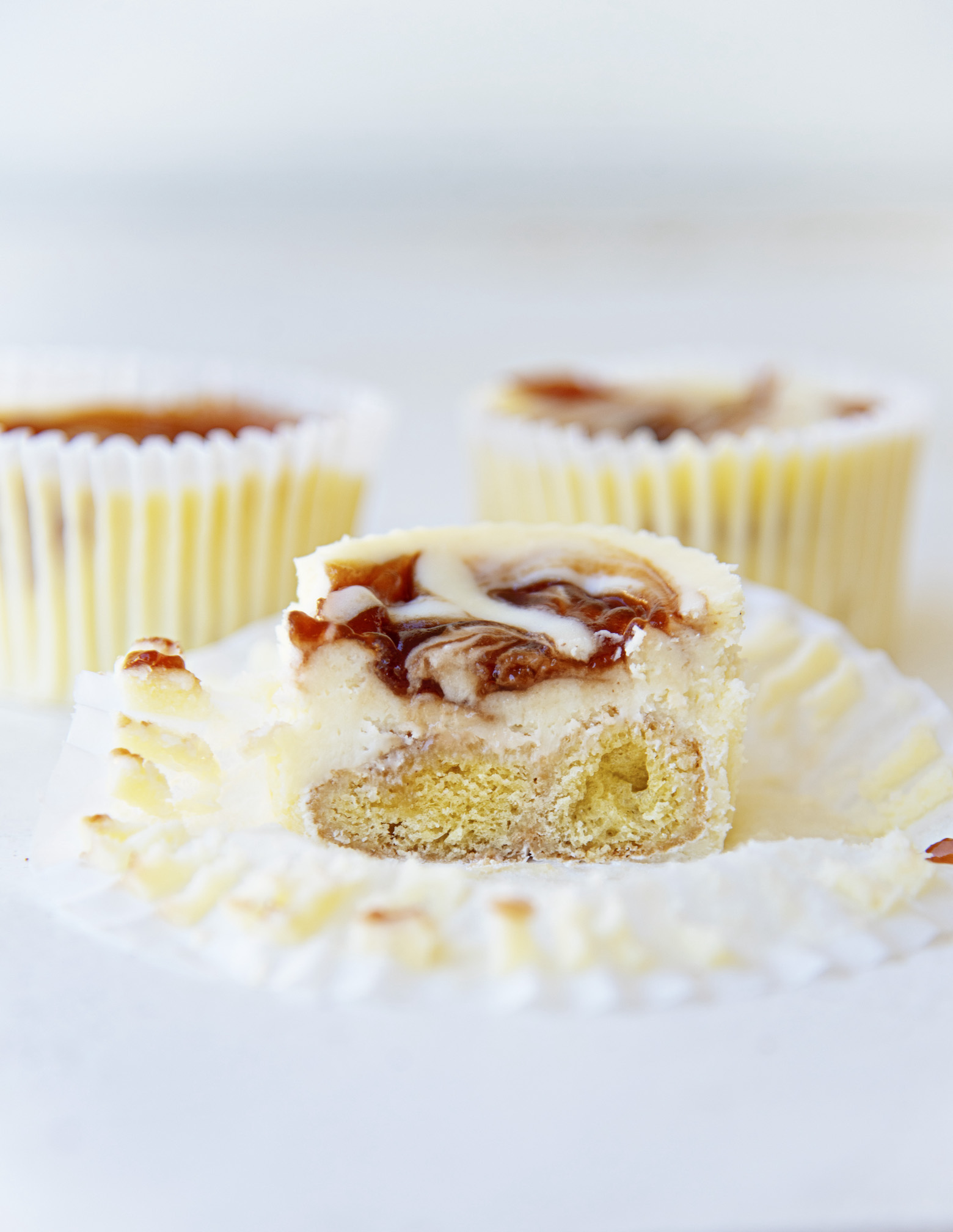 Three Powdered Jelly Donut Cheesecake Bites with the front center one cut in half to expose filling. 