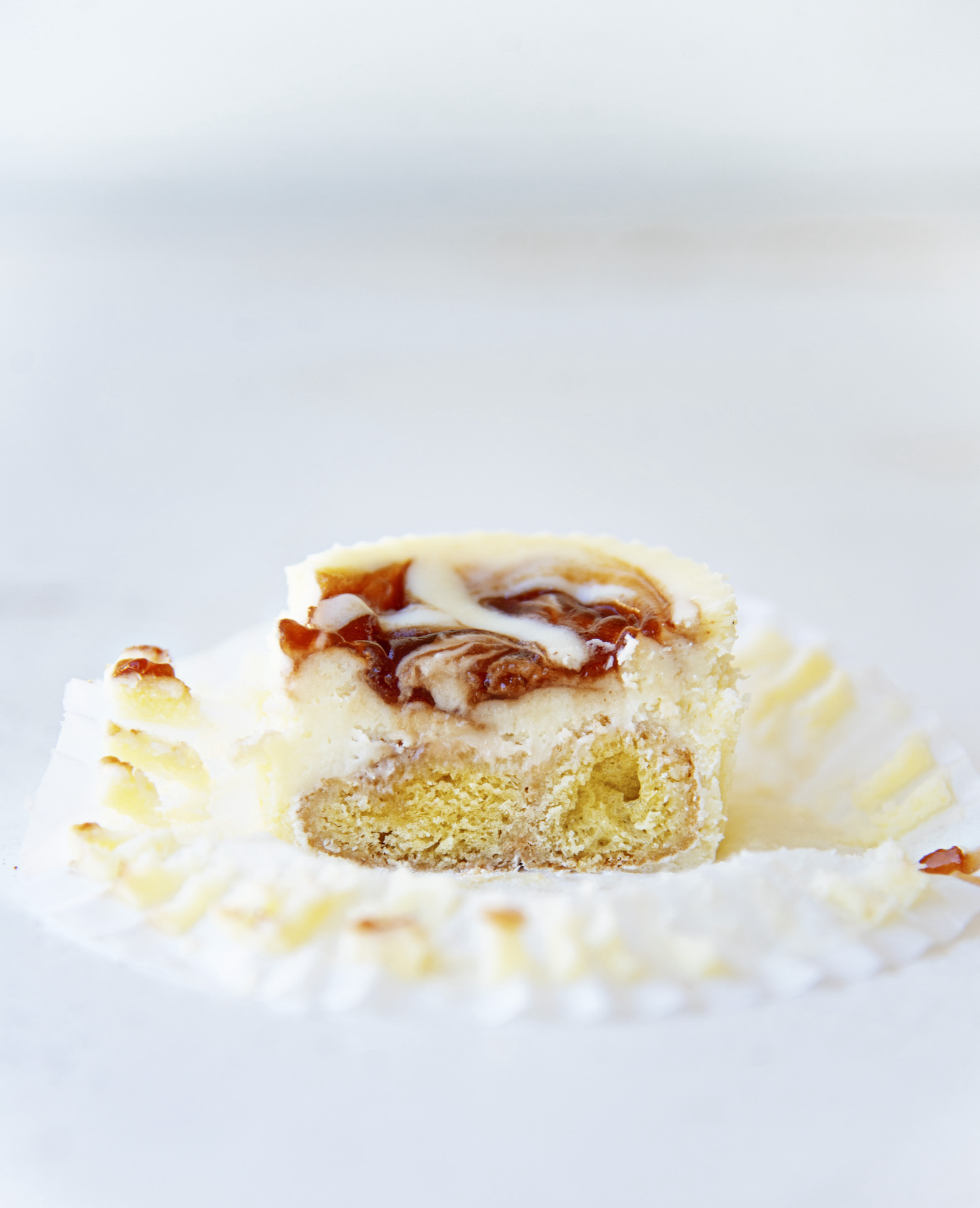 Single Powdered Jelly Donut Cheesecake Bite with it cut in half to expose filling. 