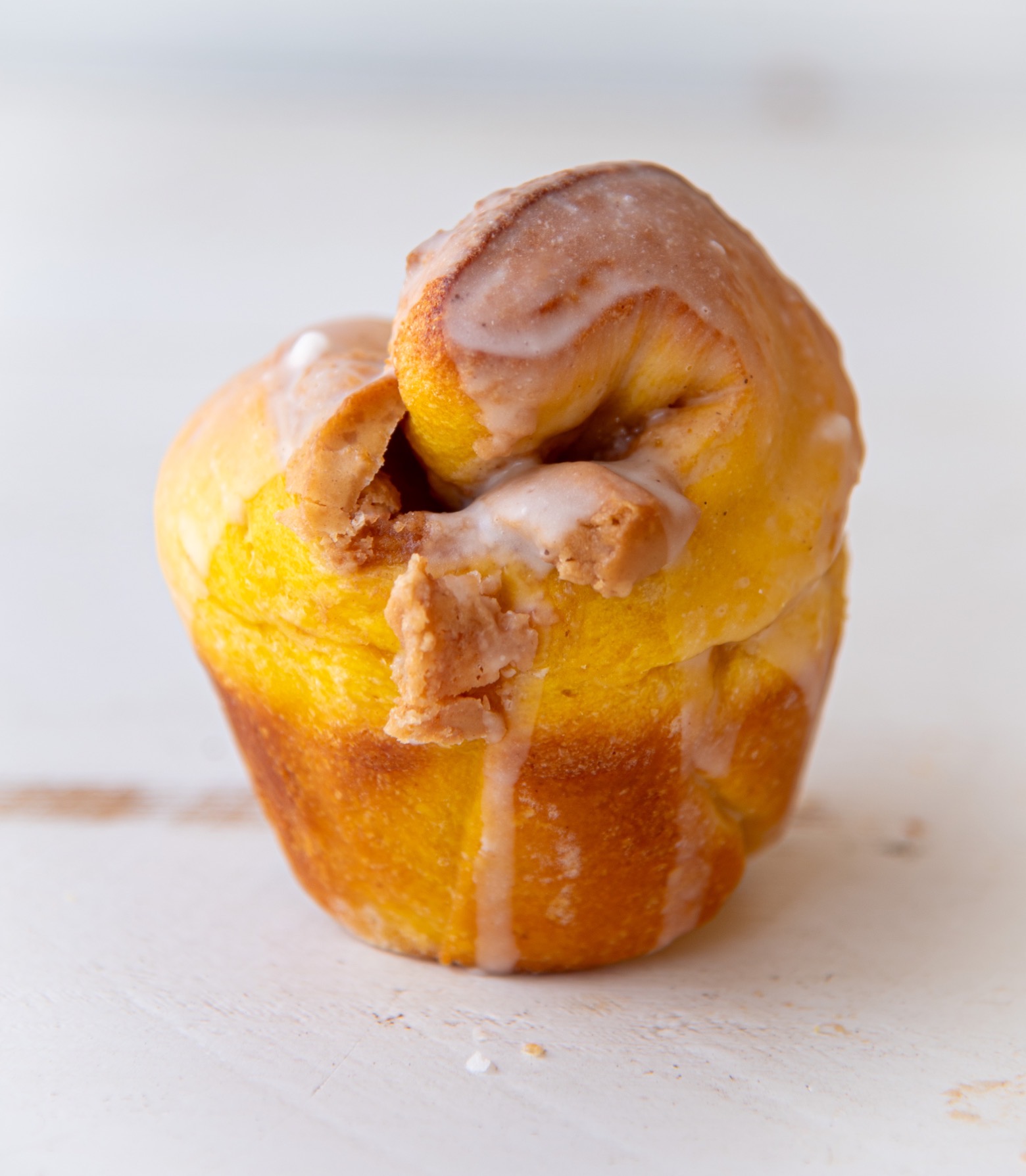 Close up of a single Pumpkin Cinnamon Crunch Bun showing the crunchy center oozing out. 