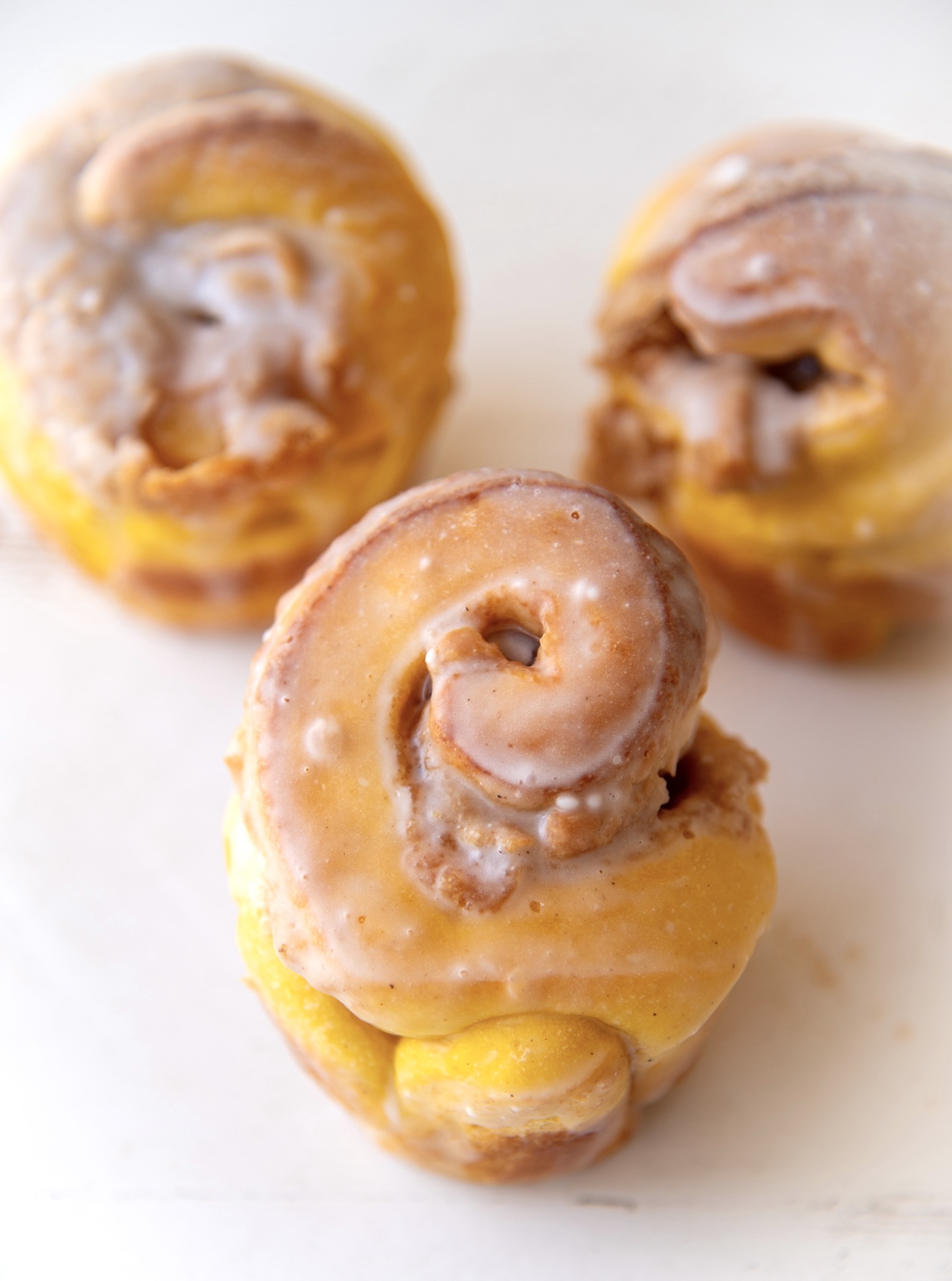 Three quarter shot of the three pumpkin brioche buns with focus on the first bun show it’s swirl. 