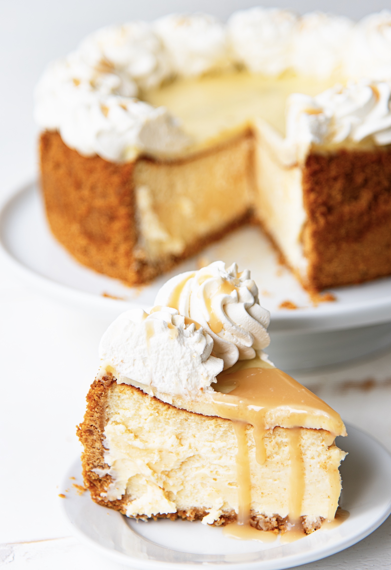 Slice of cheesecake with caramel dripping down the sides with remaining lemon sweet tea caramel cheesecake in the background. 