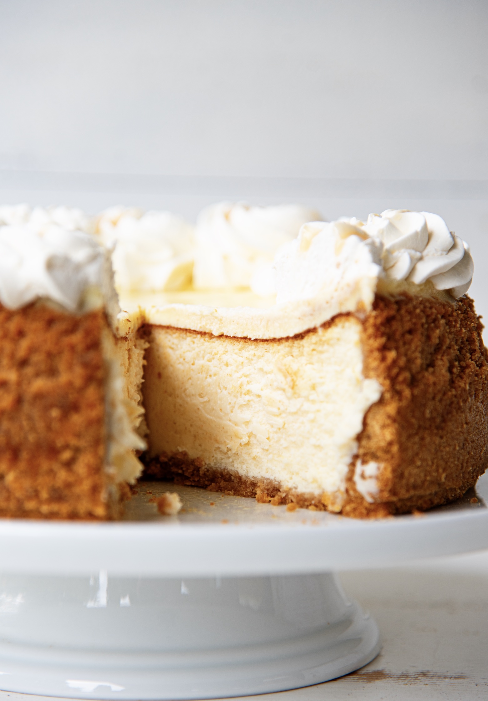 Side view of cheesecake with a piece cut out of it exposing the filling. 