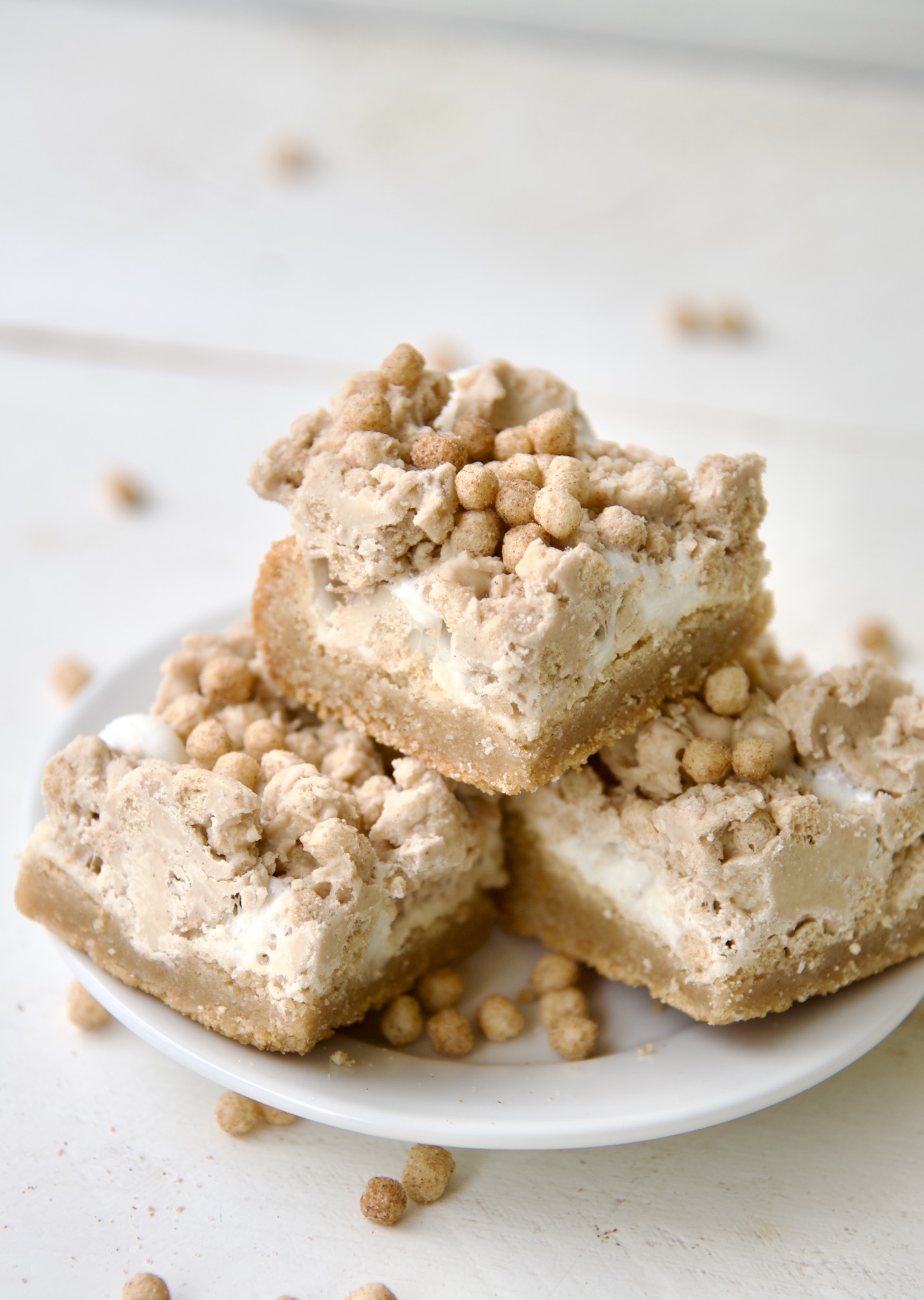 Close up of three Cinnamon Toast Cereal Marshmallow Bars on a small white plate. 