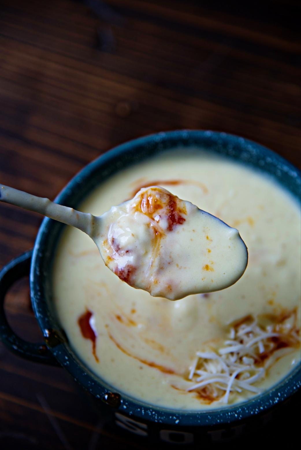 Close up of spoon coming up from the bowl with both soup and tomato jam on the spoon.